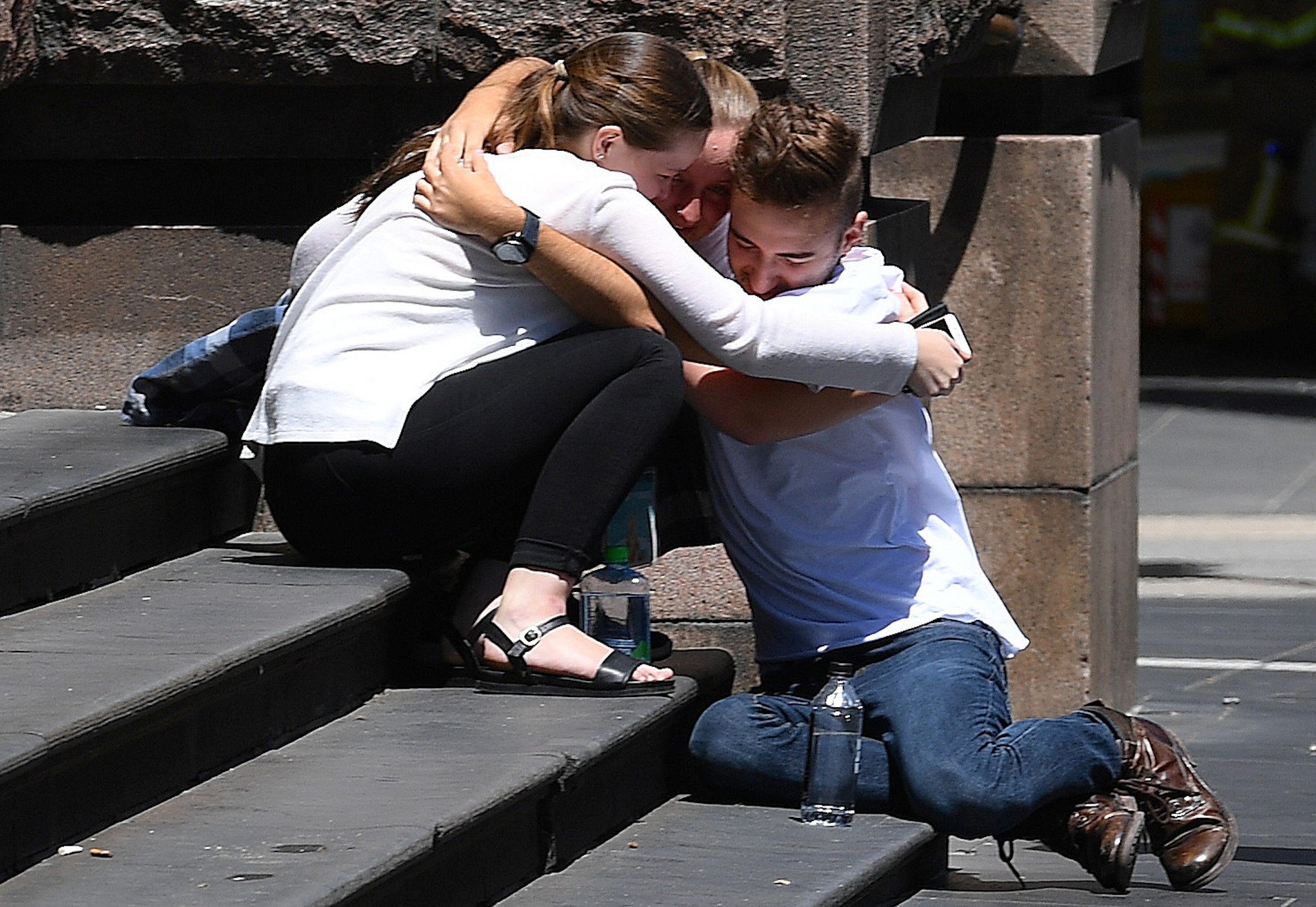 Pedestrians hug on the steps of a building near the road where a car hit pedestrians in central Melbourne, Australia, January 20, 2017. AAP/Julian Smith/via REUTERS ATTENTION EDITORS - THIS IMAGE WAS PROVIDED BY A THIRD PARTY. EDITORIAL USE ONLY. NO RESALES. NO ARCHIVE. AUSTRALIA OUT. NEW ZEALAND OUT.