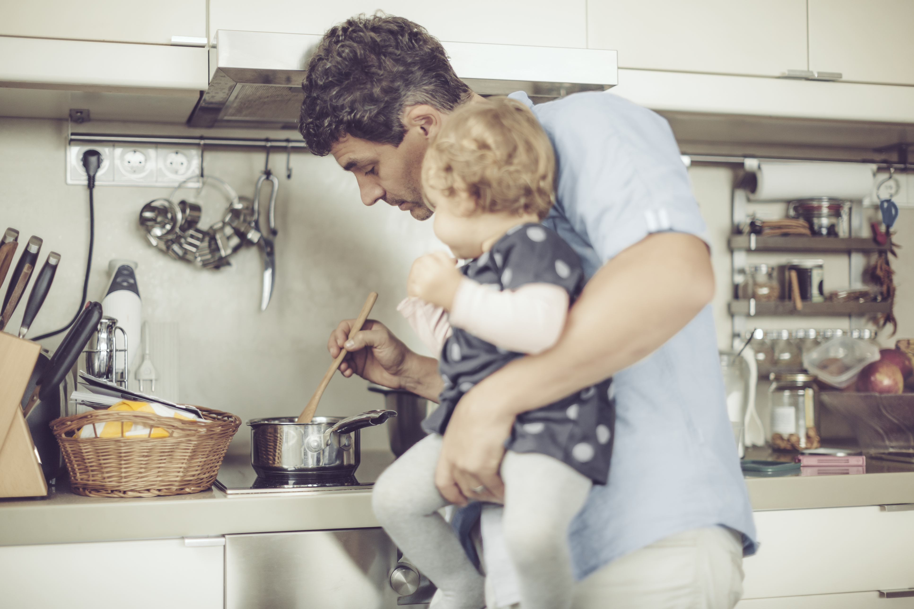 Father is cooking with his little daughter in the kitchen at home.