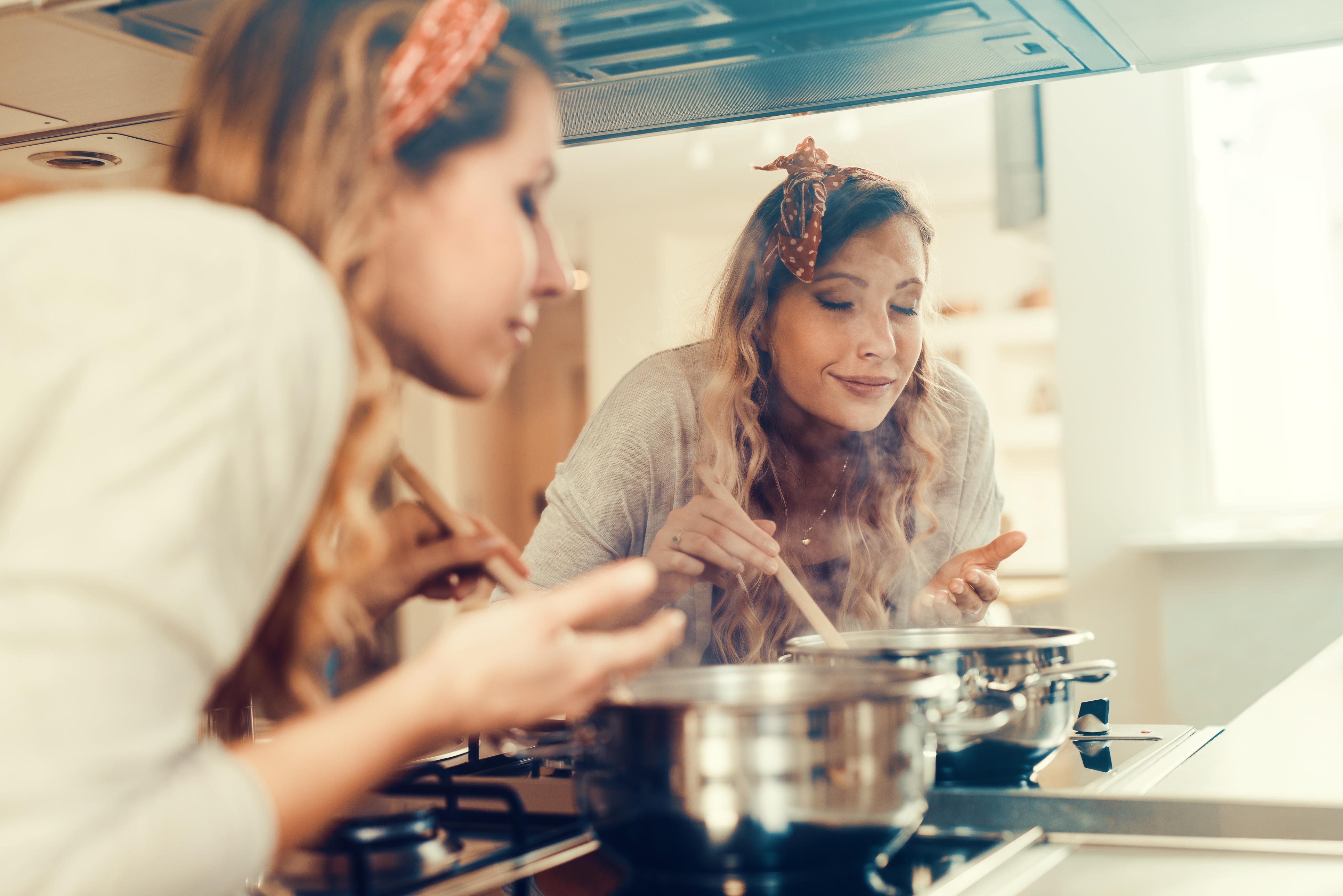 Young women cooking and testing the food in the kitchen.