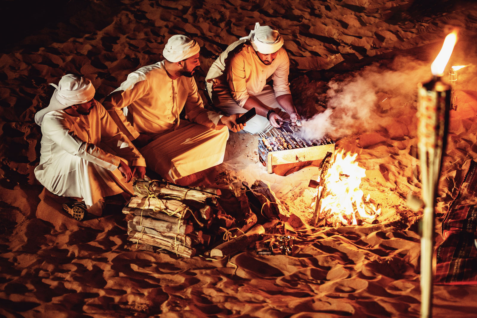 Brotherhood, Friends, Arabs, Dubai - Arab Friends Seated Around the Bonfire at a Desert Camp and Enjoying a Casual Conversation