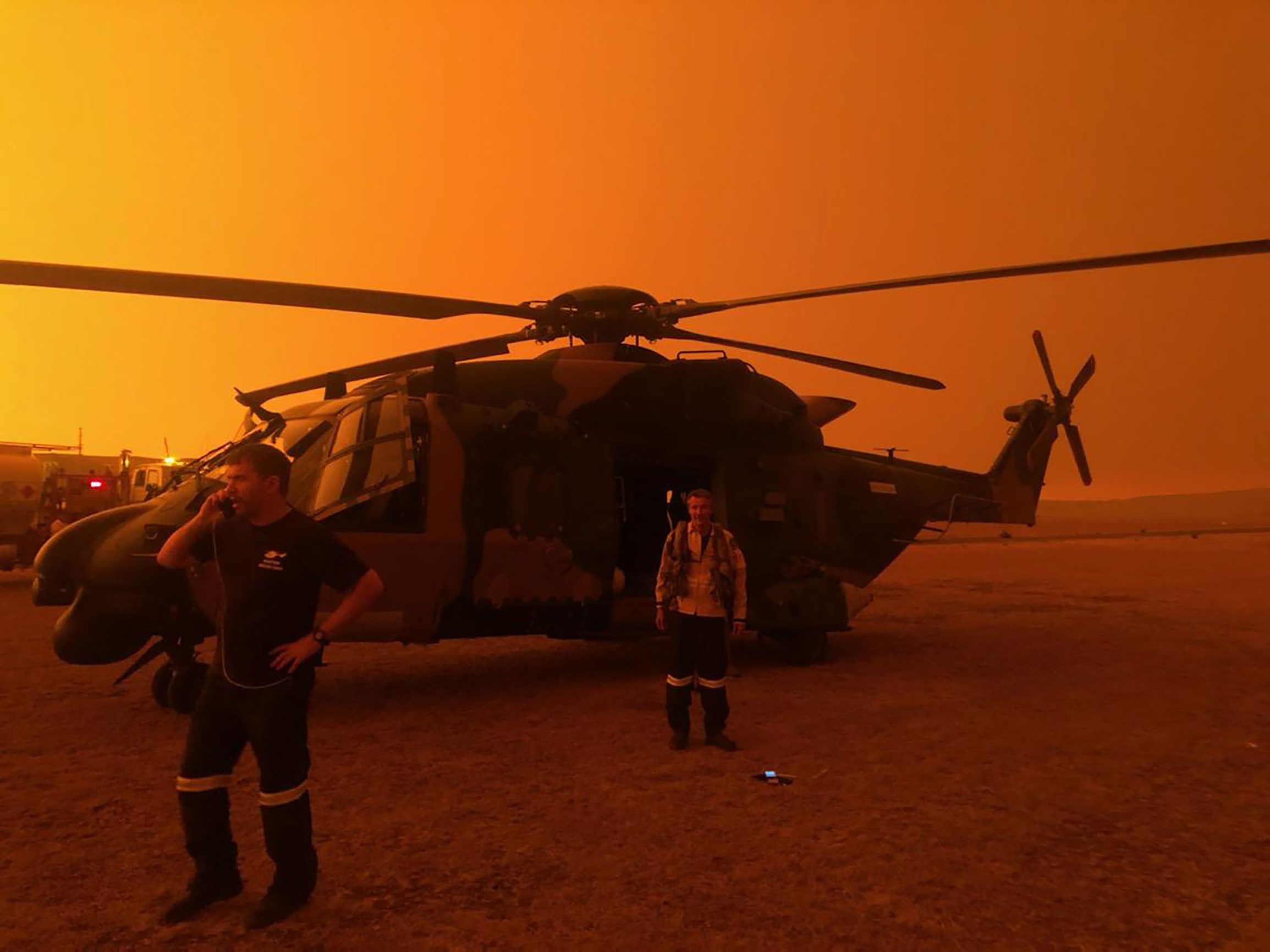 This undated handout photo received on January 5, 2020 from the Australian Department of Defence shows red skies from bushfires hanging over an Army 6 Aviation Regiment MRH-90 at Polo Flat, Cooma, during bushfire relief efforts. - Australians on January 5 counted the cost from a day of catastrophic bushfires that caused 