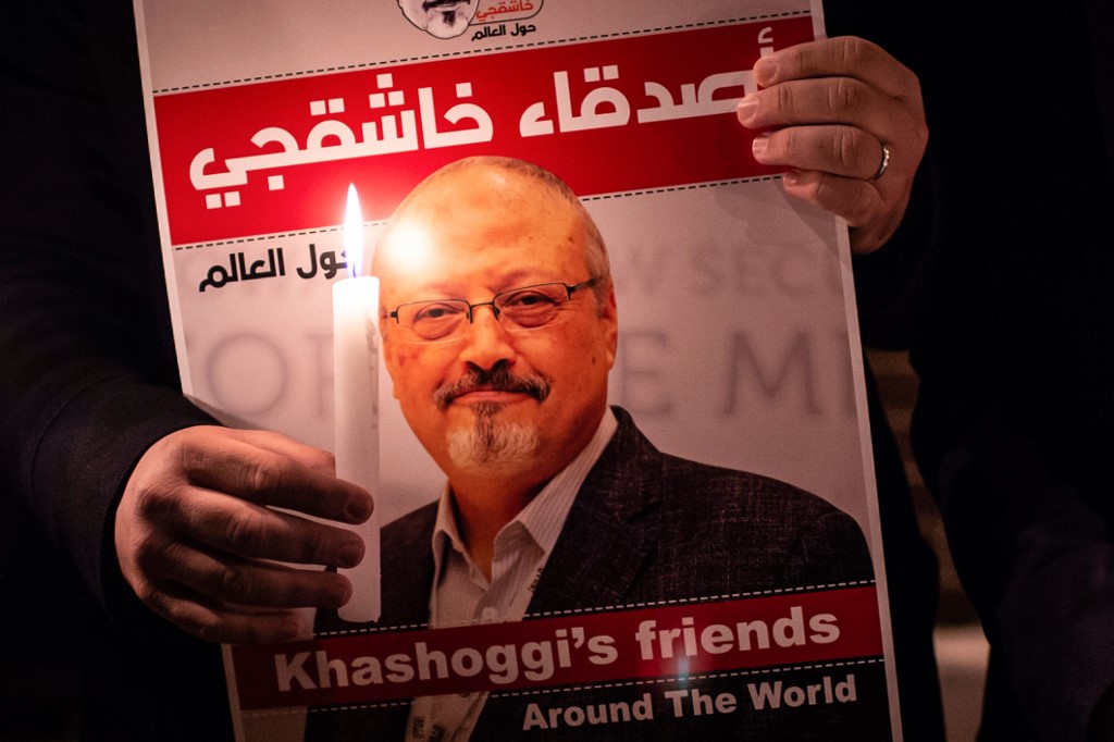 A demonstrator holds a poster picturing Saudi journalist Jamal Khashoggi and a lightened candle during a gathering outside the Saudi Arabia consulate in Istanbul, on October 25, 2018. - Jamal Khashoggi, a Washington Post contributor, was killed on October 2, 2018 after a visit to the Saudi consulate in Istanbul to obtain paperwork before marrying his Turkish fiancee. (Photo by Yasin AKGUL / AFP)