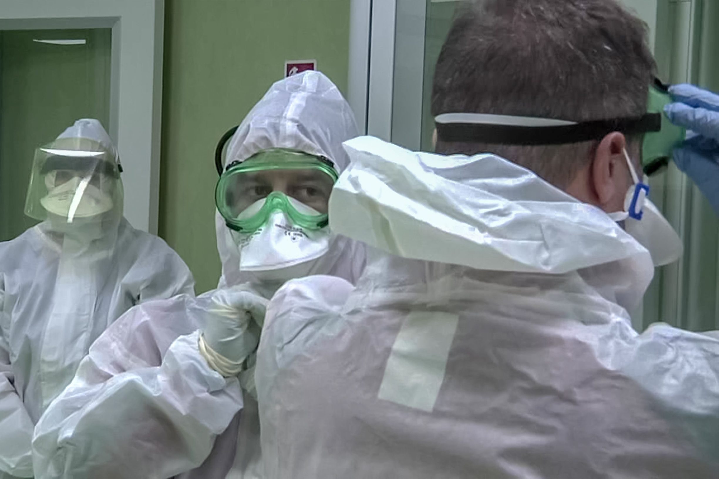 This photo grabbed from a video taken and handout on January 23, 2020 by Rome's Fiumicino Airport Authority (ADR) shows members of the Italian Red Cross putting on their protective gear, getting ready to apply health measures and procedures against deadly SARS-like virus outbreak risks, on passengers that landed at Rome's Fiumicino airport on a southern airlines flight from Wuhan, China. - China banned trains and planes from leaving a major city at the centre of a virus outbreak on January 23, seeking to seal off its 11 million people to contain the contagious disease that has claimed 17 lives, infected hundreds and spread to other countries. (Photo by Handout / AEROPORTO DI ROMA / AFP) / RESTRICTED TO EDITORIAL USE - MANDATORY CREDIT 