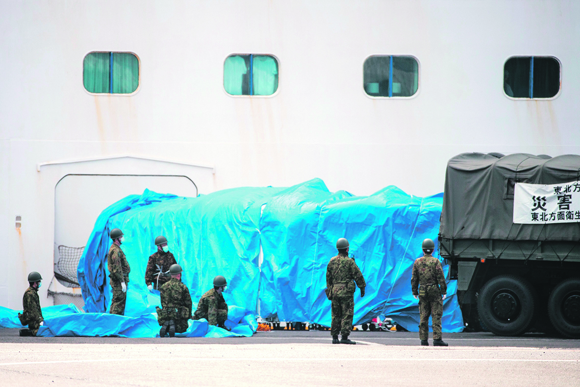 Members of Japan Self-Defense Force attach a military vehicle to a gate of the Diamond Princess cruise ship, with around 3,600 people quarantined onboard due to fears of the COVID-19 coronavirus, at the Daikaku Pier Cruise Terminal in Yokohama port on February 12, 2020. - A further 39 people on board the Diamond Princess cruise ship off the Japan coast have tested positive for the new coronavirus, authorities said on February 12, as thousands more steel themselves for a second week in quarantine. (Photo by Behrouz MEHRI / AFP)