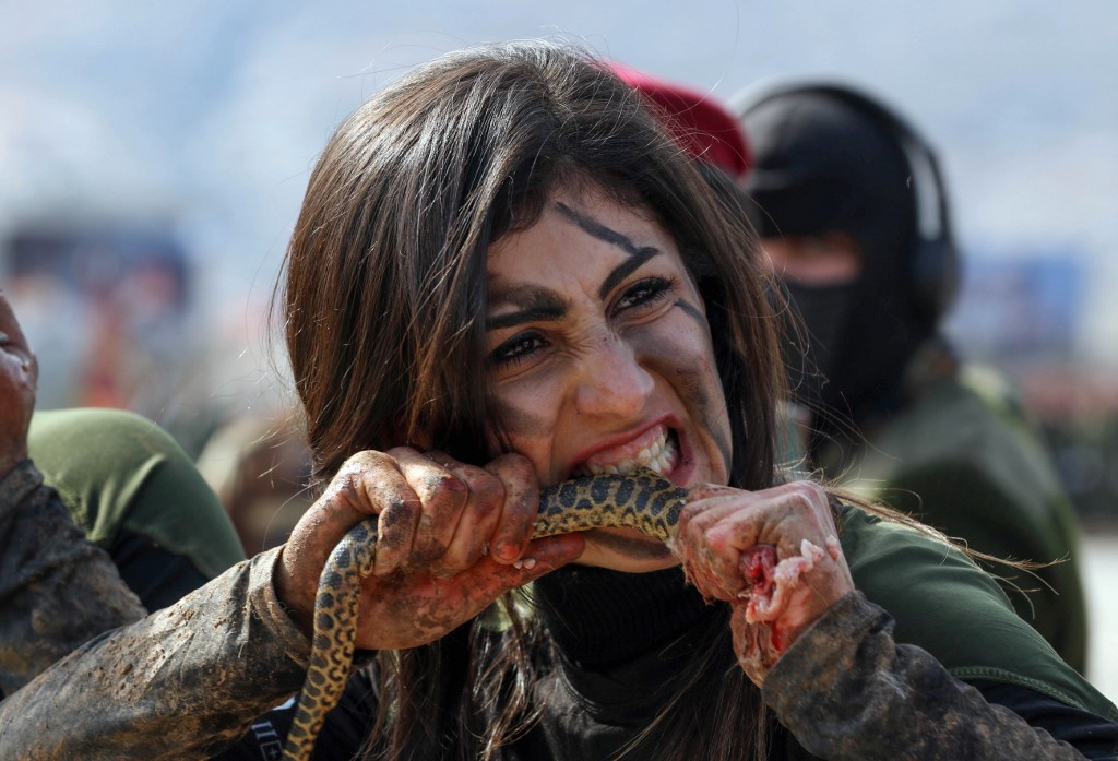 An Iraqi Kurdish Peshmerga female officer bites a snake while demonstrating skills during a graduation ceremony in the Kurdish town of Soran, about 100 kilometres northeast of the capital of Iraq's autonomous Kurdish region Arbil, on February 12, 2020. (Photo by SAFIN HAMED / AFP)
