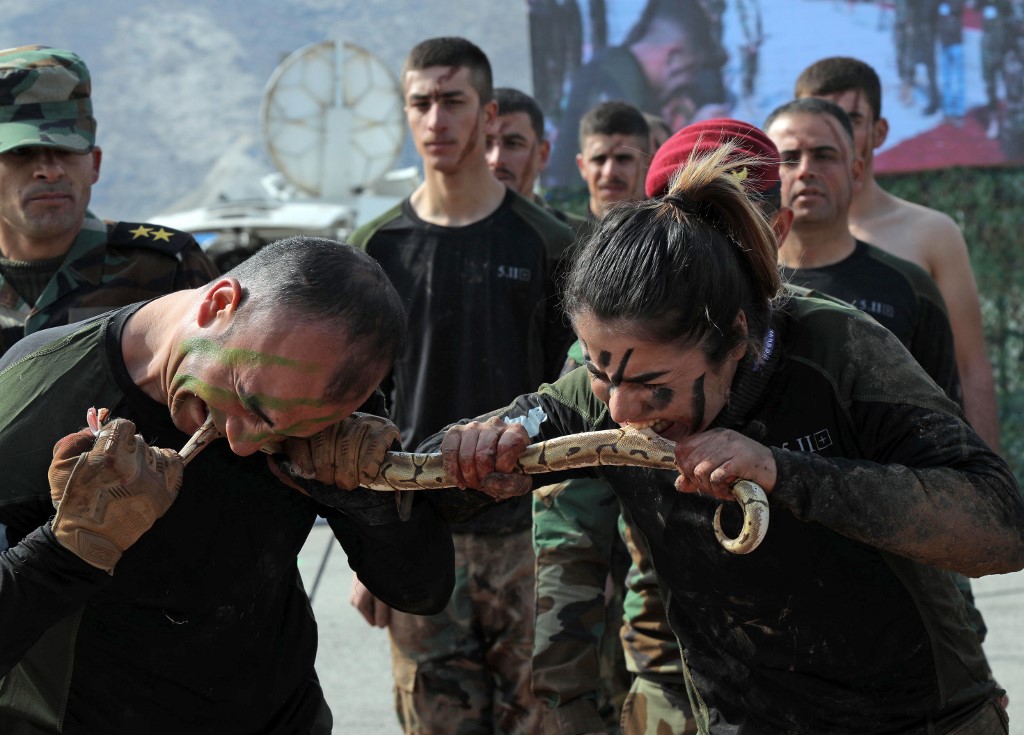 Iraqi Kurdish Peshmerga officers bite a snake while demonstrating skills during a graduation ceremony in the Kurdish town of Soran, about 100 kilometres northeast of the capital of Iraq's autonomous Kurdish region Arbil, on February 12, 2020. (Photo by SAFIN HAMED / AFP)