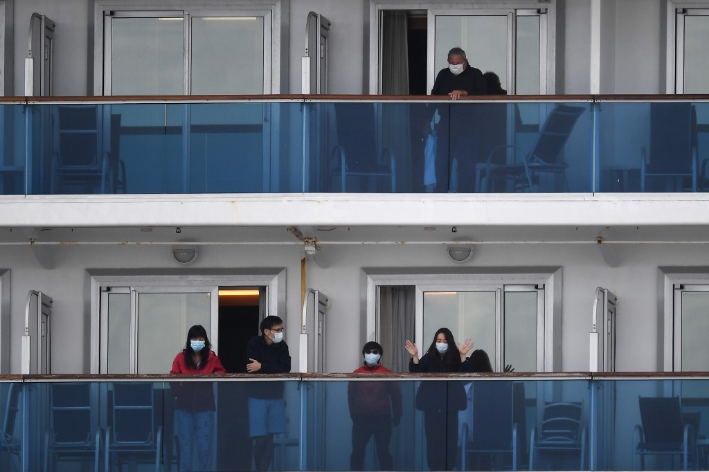 Passengers look out from the balconies of the Diamond Princess cruise ship - in quarantine due to fears of the new COVID-19 coronavirus - as a the first group of passengers (not pictured) disembark from the ship at the Daikoku Pier Cruise Terminal in Yokohama on February 19, 2020. - Relieved passengers began leaving a coronavirus-wracked cruise ship in Japan on February 19 after testing negative for the disease that has now claimed more than 2,000 lives in China. (Photo by CHARLY TRIBALLEAU / AFP)