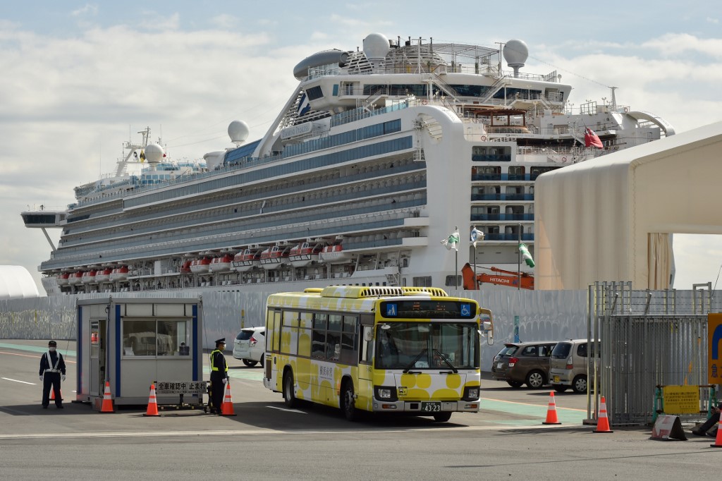 A bus carrying passengers who disembarked from the Diamond Princess cruise ship (back) in quarantine due to fears of the new COVID-19 coronavirus, leaves the Daikoku Pier Cruise Terminal in Yokohama on February 19, 2020. - Relieved passengers began leaving a coronavirus-wracked cruise ship in Japan on February 19 after testing negative for the disease that has now claimed more than 2,000 lives in China. (Photo by Kazuhiro NOGI / AFP)