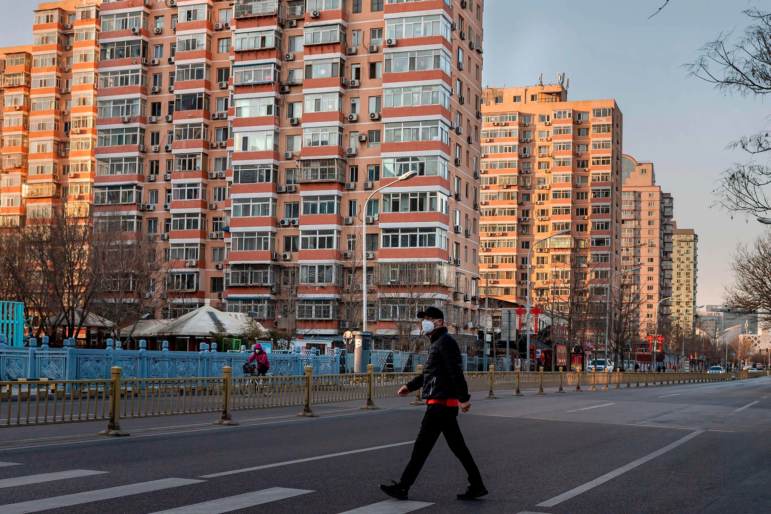 A man wearing a protective mask walks along an empty street in Beijing on January 31, 2020, following a SARS-like virus outbreak which began in the Chinese city of Wuhan. - The World Health Organization declared an international emergency after China's National Health Commission said nearly 8,000 people had been infected, and about 100 cases were reported outside China. (Photo by NICOLAS ASFOURI / AFP)