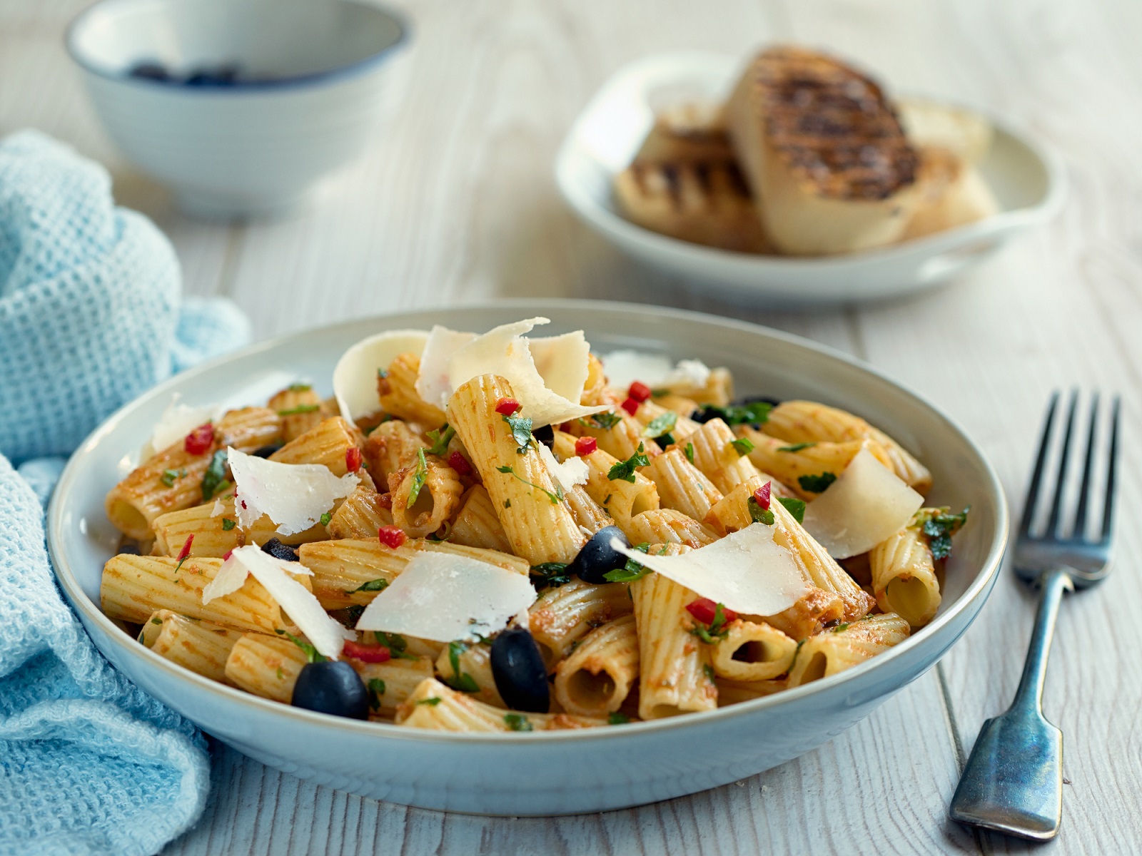 Home made freshness rigatoni pasta salad with red pesto chilli sauce and black olives,service with shaved parmesan cheese and  toasted ciabatta bread