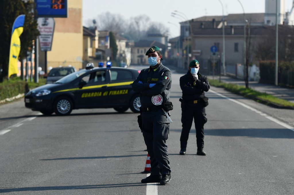 Italian Finance guards (Guardia di Finanza) officers patrol by a check-point at the entrance of the small town of Zorlesco, southeast of Milan, on February 24, 2020, situated in the red zone of the COVID-19 the novel coronavirus outbreak in northern Italy. - Italy, the country with the most confirmed cases in Europe, reports its fifth death and the number of people contracting the disease continues to mount, with 219 people now testing positive. (Photo by Miguel MEDINA / AFP)
