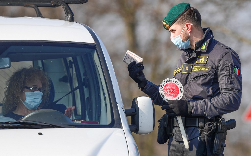 An Italian Finance guard (Guardia di Finanza) conducts control and gives indications to drivers at a check-point at the entrance of the small town of Zorlesco, southeast of Milan, on February 24, 2020, situated in the red zone of the COVID-19 the novel coronavirus outbreak in northern Italy. - Italy, the country with the most confirmed cases in Europe, reports its fifth death and the number of people contracting the disease continues to mount, with 219 people now testing positive. (Photo by Miguel MEDINA / AFP)