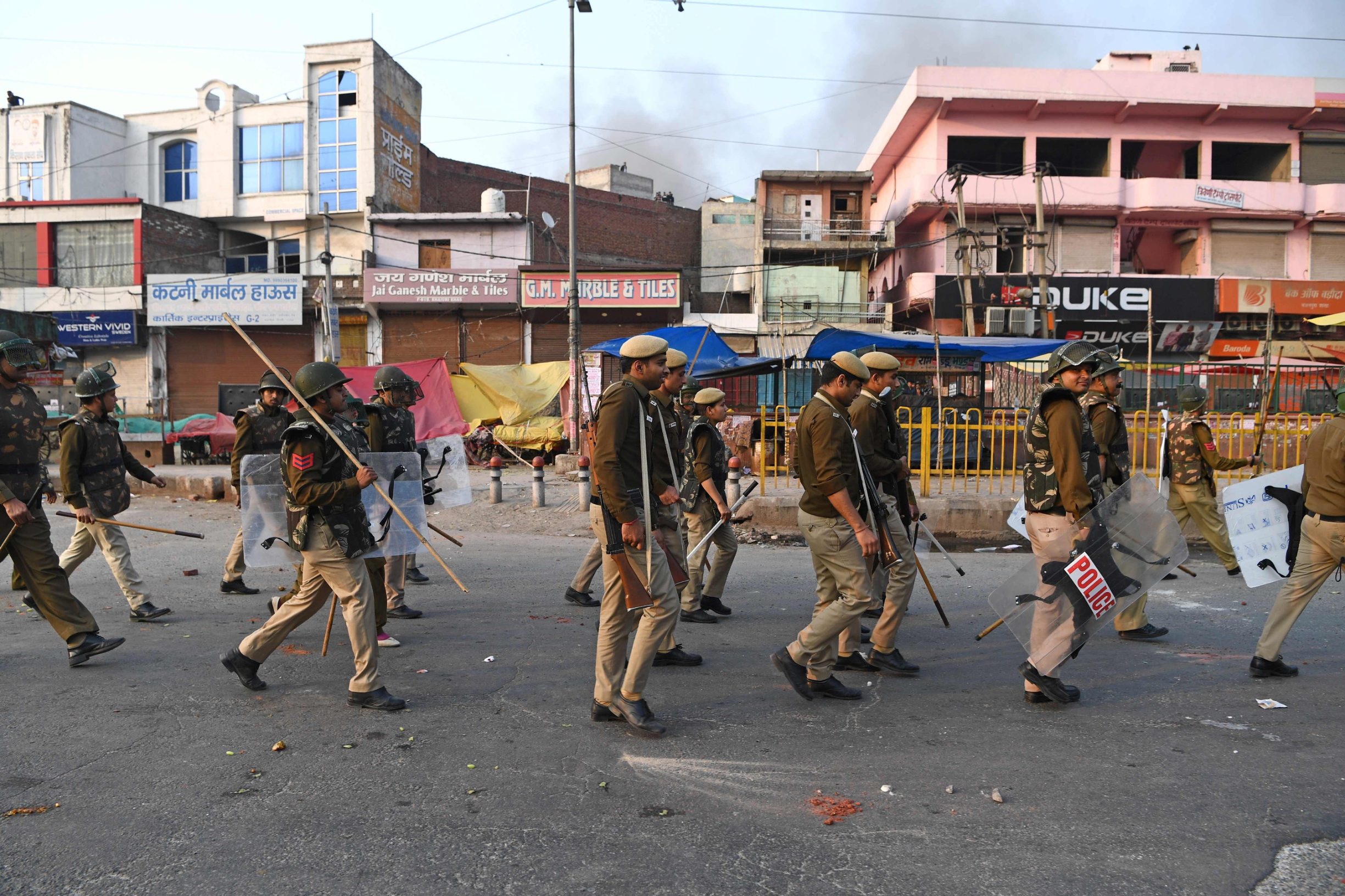 Policemen march as they patrol a road following clashes between supporters and opponents of a new citizenship law, at Bhajanpura area of New Delhi on February 24, 2020, ahead of US President arrival in New Delhi. - Fresh clashes raged in New Delhi in protests over a contentious citizenship law on February 24, hours ahead of a visit to the Indian capital by US President Donald Trump. India has seen weeks of demonstrations and violence since a new citizenship law -- that critics say discriminates against Muslims -- came into force in December. (Photo by Sajjad  HUSSAIN / AFP)