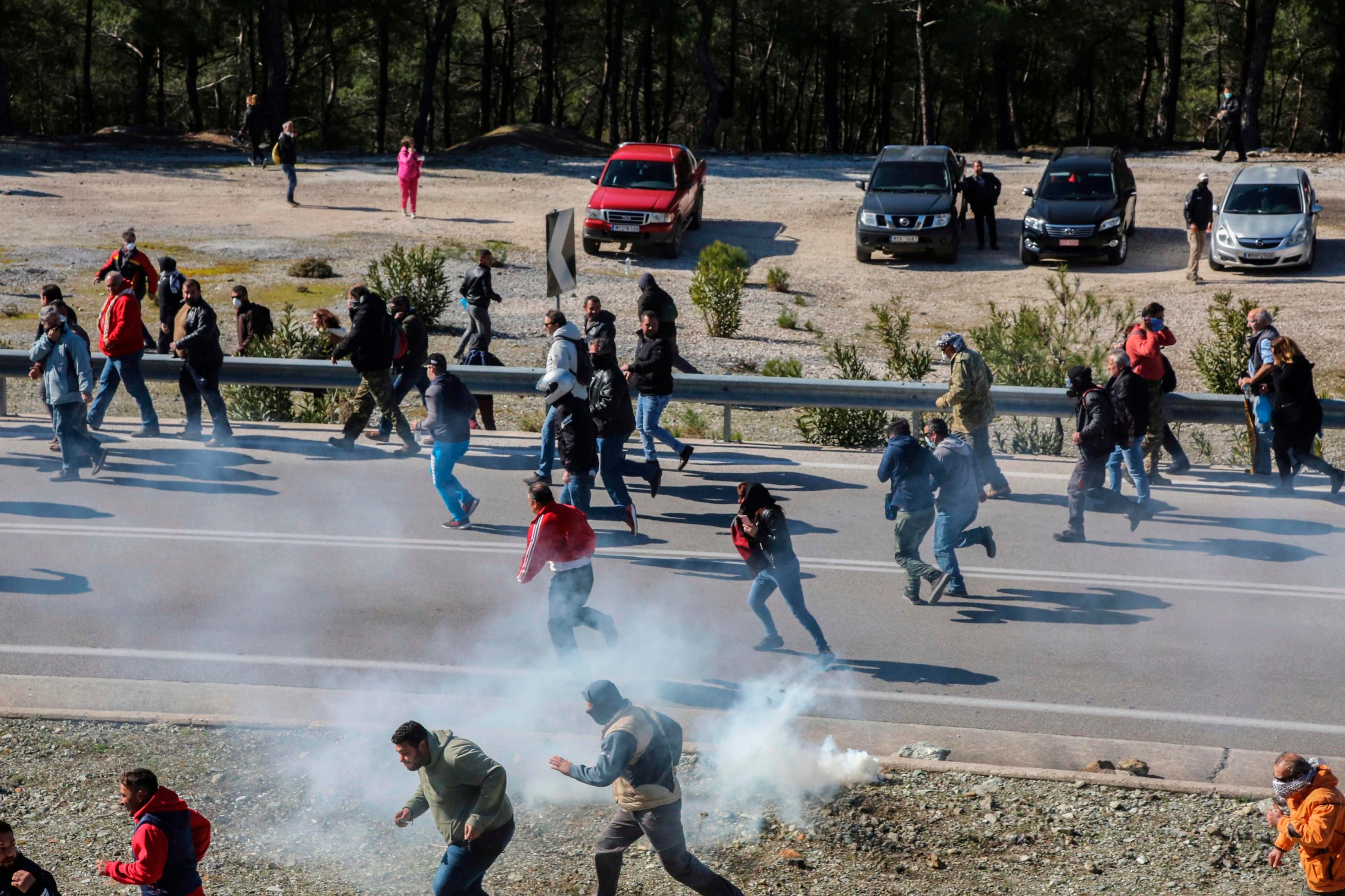 Demonstrators run during a protest against the construction of a new controversial migrant camp near the town of Mantamados on the northeastern Aegean island of Lesbos, on February 26, 2020. - The Greek islands of Lesbos, Chios and Samos staged a general strike on February 26, as protests against the construction of new migrant camps intensified. For a second day, protesters on Lesbos faced off against riot police near the town of Mantamados, close to the site of a planned camp for up to 7,000 people. Small groups of protesters threw stones and firebombs at the police, who responded with tear gas and flash grenades. (Photo by Manolis LAGOUTARIS / AFP)