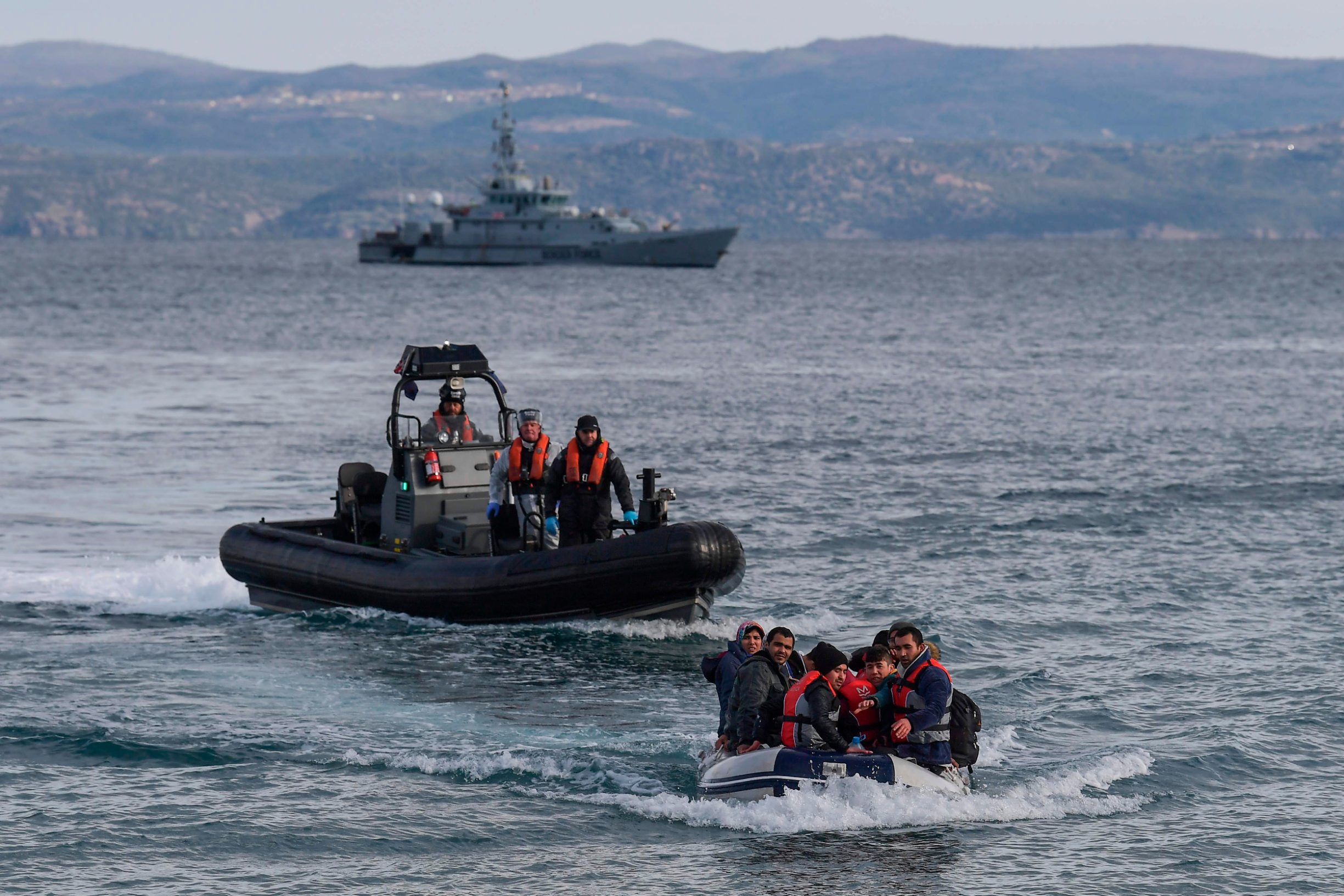 A dinghy with 15 Afghan refugees, 5 children, 3 women and 7 men, approaches the Greek island of Lesbos on February 28, 2020 next to UK Border Force patrol boat HMC Valiant (background), a cutter patroling in Agean sea under European Union border force Frontex. - Turkey will no longer close its border gates to refugees who want to go to Europe, a senior official told AFP on February 28, shortly after the killing of 33 Turkish soldiers in an airstrike in northern Syria. (Photo by ARIS MESSINIS / AFP)