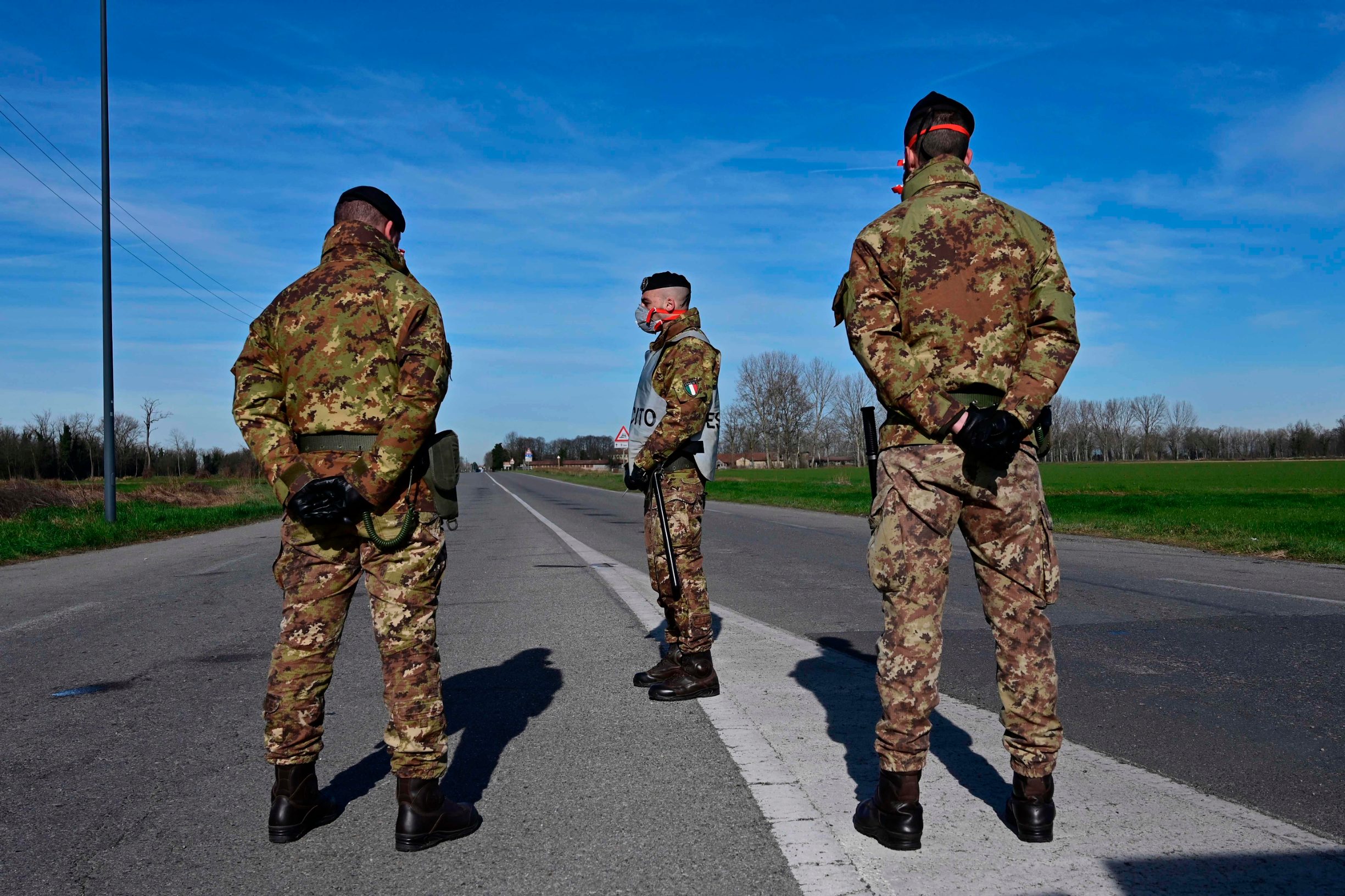 Italian Army soldiers wearing protective masks check transit to and from the cordoned areas in a check-point few kilometers from the small town of Castiglione d'Adda, southeast of Milan, on February 27, 2020 amid fears over the spread of the novel Coronavirus. - The number of COVID-19 infections in Italy, the hardest hit country in Europe, hits the 400 mark late on February 26, with 12 deaths. (Photo by Miguel MEDINA / AFP)