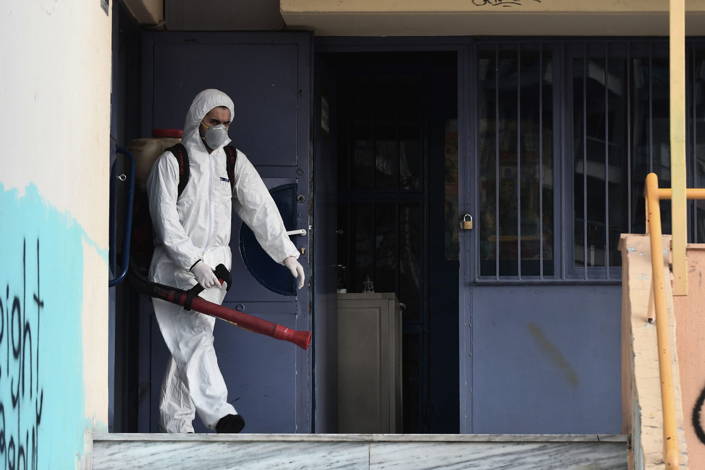 A worker walks out as he sprays  disinfectant as part of preventive measures against the spread of the COVID-19, the novel coronavirus, in a school in Thessaloniki, northern Greece, on February 27, 2020. - The Greek health ministry said a boy whose 38-year-old mother is already hospitalised with the virus after returning from a trip to northern Italy where there are several cases of the virus had also tested positive in Thessaloniki. The boy's school in Thessaloniki will be shut for two weeks and his entire class will stay at home, the school's principal told state TV ERT. (Photo by Sakis MITROLIDIS / AFP)