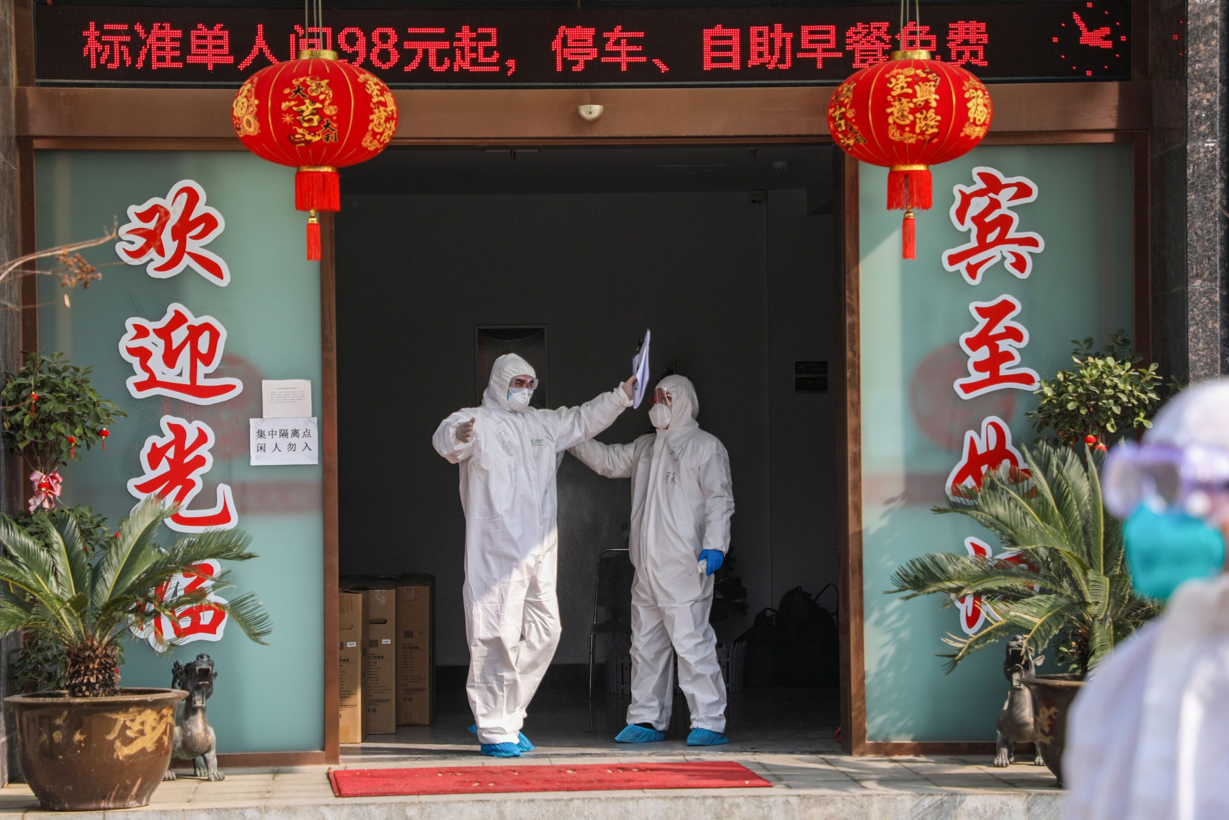 This photo taken on February 3, 2020 shows a medical staff member (L) being disinfected by a colleague before leaving a quarantine zone converted from a hotel in Wuhan, the epicentre of the new coronavirus outbreak, in China's central Hubei province. - The number of total infections in China's coronavirus outbreak has passed 20,400 nationwide with 3,235 new cases confirmed, the National Health Commission said on February 4. (Photo by STR / AFP) / China OUT