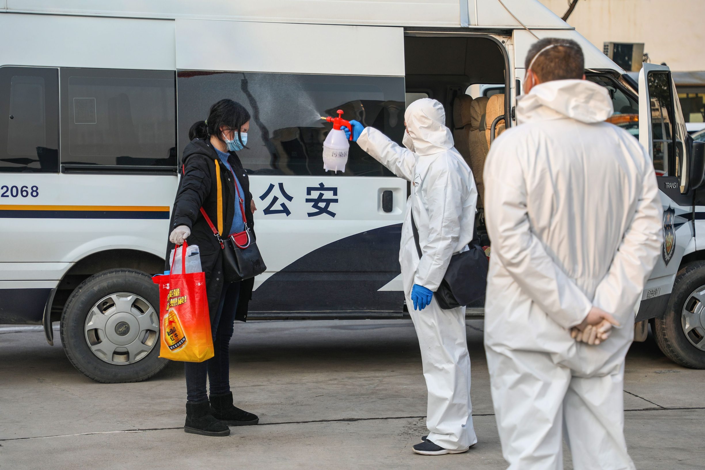 This photo taken on February 3, 2020 shows a medical staff member (C) spraying disinfectant on a patient after returning from a hospital and re-entering a quarantine zone in Wuhan, the epicentre of the new coronavirus outbreak, in China's central Hubei province. - The number of total infections in China's coronavirus outbreak has passed 20,400 nationwide with 3,235 new cases confirmed, the National Health Commission said on February 4. (Photo by STR / AFP) / China OUT