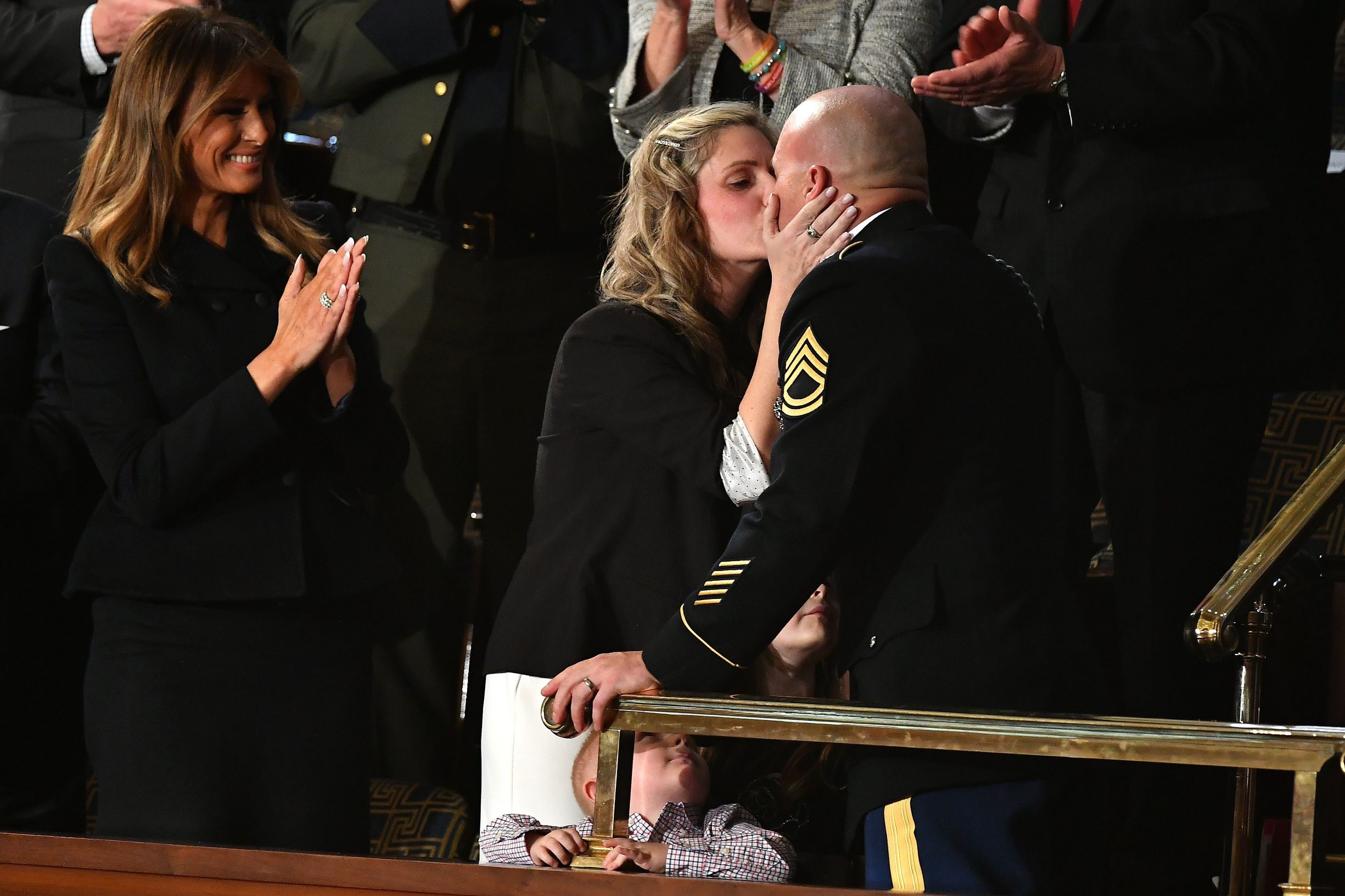 Sgt Townsend Williams (R) kisses his wife Amy (C) after returning from deployment in Afghanistan as First Lady Melania Trump applauds during the State of the Union address at the US Capitol in Washington, DC, on February 4, 2020. (Photo by MANDEL NGAN / AFP)