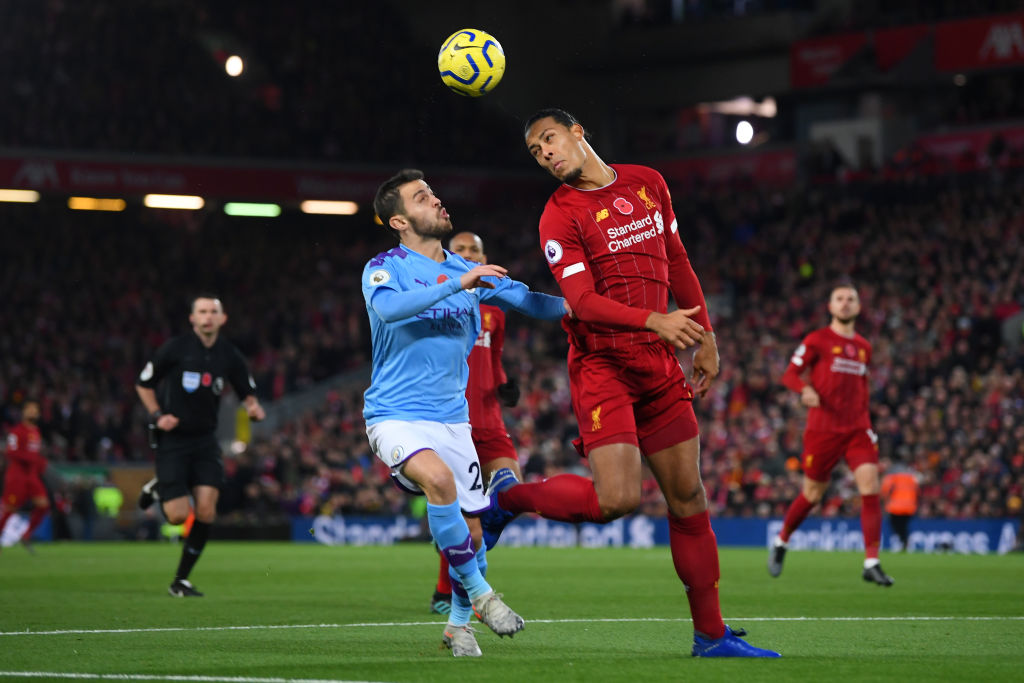 LIVERPOOL, ENGLAND - NOVEMBER 10: Virgil van Dijk of Liverpool heads the ball clear as he is put under pressure by Bernardo Silva of Manchester City during the Premier League match between Liverpool FC and Manchester City at Anfield on November 10, 2019 in Liverpool, United Kingdom. (Photo by Laurence Griffiths/Getty Images)