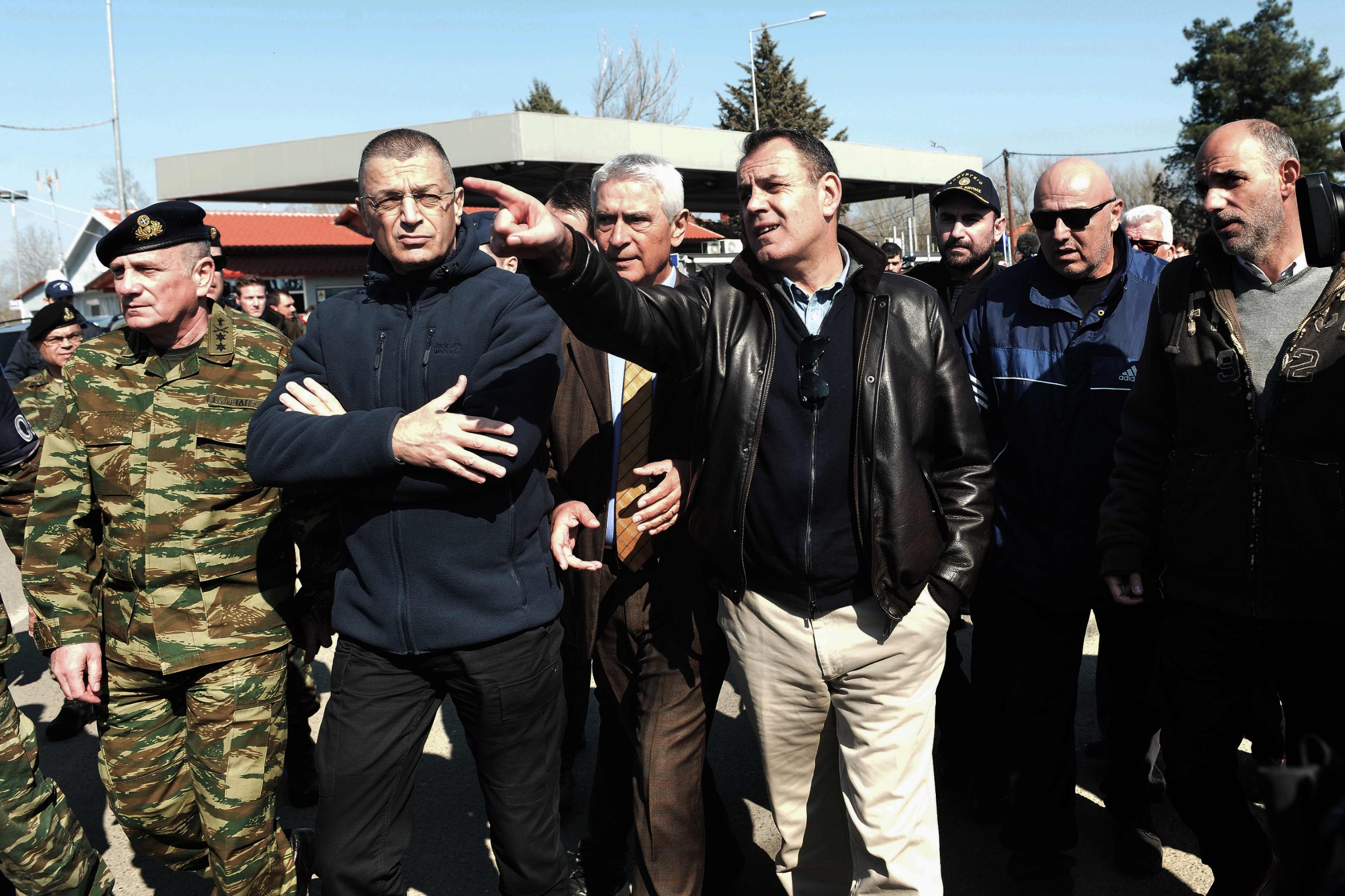 Greek Minister of defence Nikos Panagiotopoulos (C-R) walks in the village of Kastanies on March 1, 2020. - Thousands more migrants reached the Turkish border with Greece on March 1, 2020, AFP journalists said, after President threatened to let them cross into Europe. At least 2,000 people including women and children arrived on the morning from Istanbul and walked through a field towards the Pazarkule border gate, a correspondent said. The group included Afghans, Syrians and Iraqis. (Photo by Sakis MITROLIDIS / AFP)