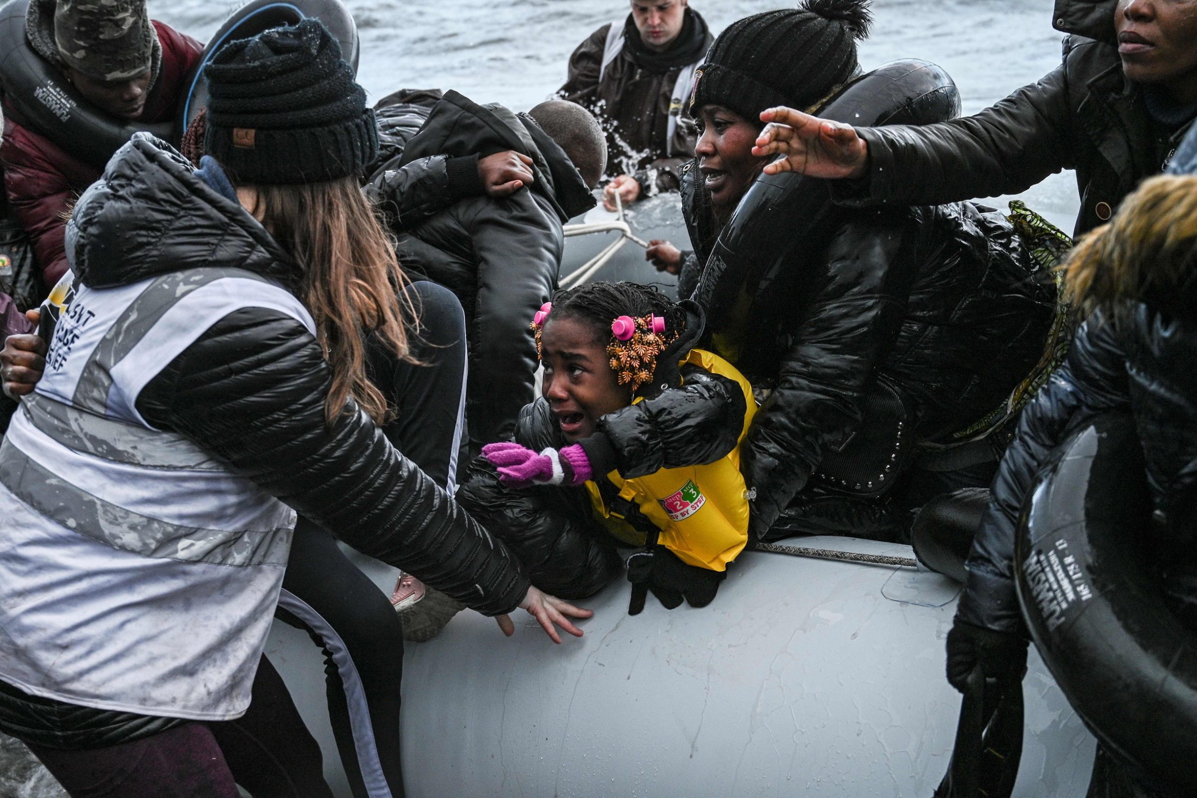TOPSHOT - An NGO member helps a girl as a dinghy transporting 27 refugees and migrants originating from Gambia and the Republic of Congo lands in Lesbos island after they were rescued by a war ship during their sea crossing between Turkey and Greece on February 29, 2020. - Greece blocked hundreds of migrants trying to enter the country on Friday after Turkey said it would open the gates for refugees from Syria to enter the European Union. Turkey's threat came hours after a Syrian strike on Thursday killed 33 of its soldiers in Idlib and was aimed at forcing European governments to do more to support it in its fight against the regime. (Photo by ARIS MESSINIS / AFP)
