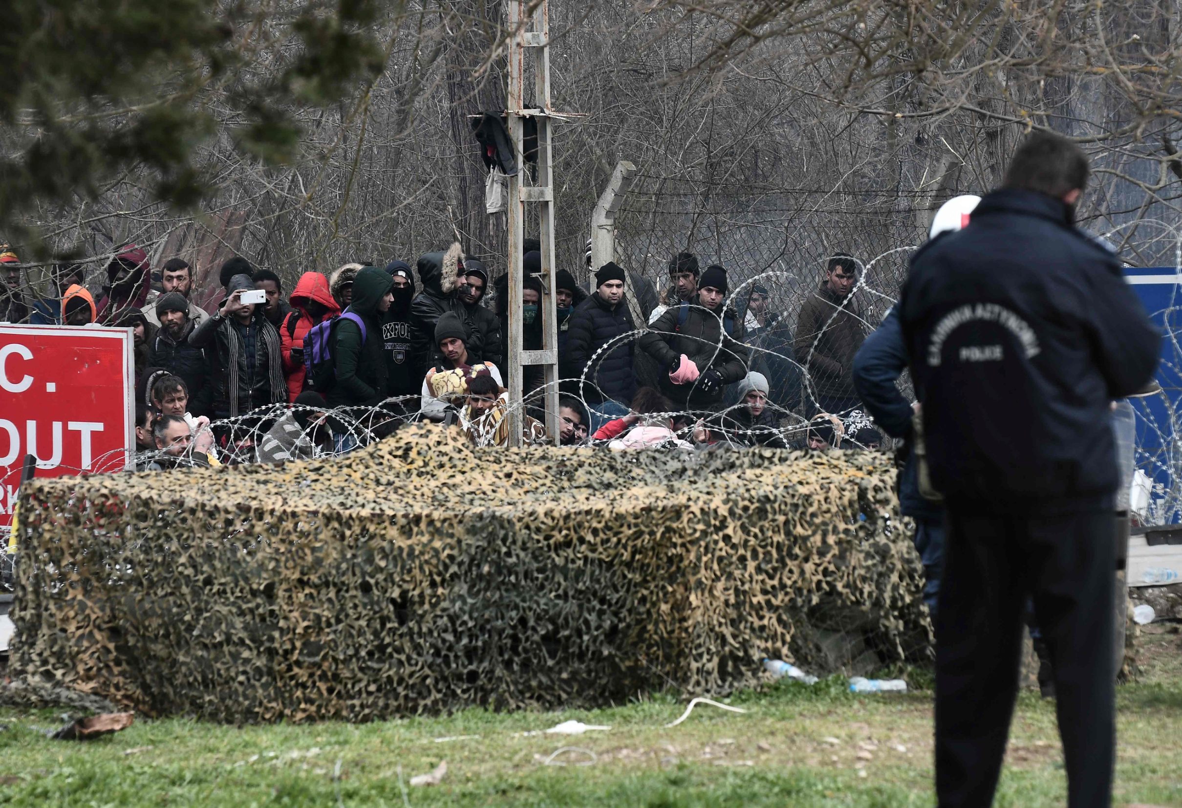 Greek police officers face migrants gathered at the Greece-Turkey border, near Kastanies, Greece, on February 29, 2020. - Thousands of migrants stuck on the Turkey-Greece border clashed with Greek police on February 29, 2020, according to an AFP photographer at the scene. Greek police fired tear gas at migrants who have amassed at a border crossing in the western Turkish province of Edirne, some of whom responded by hurling stones at the officers. The clashes come as Greece bolsters its border after Ankara said it would no longer prevent refugees from crossing into Europe following the death of 33 Turkish troops in northern Syria. (Photo by Sakis MITROLIDIS / AFP)