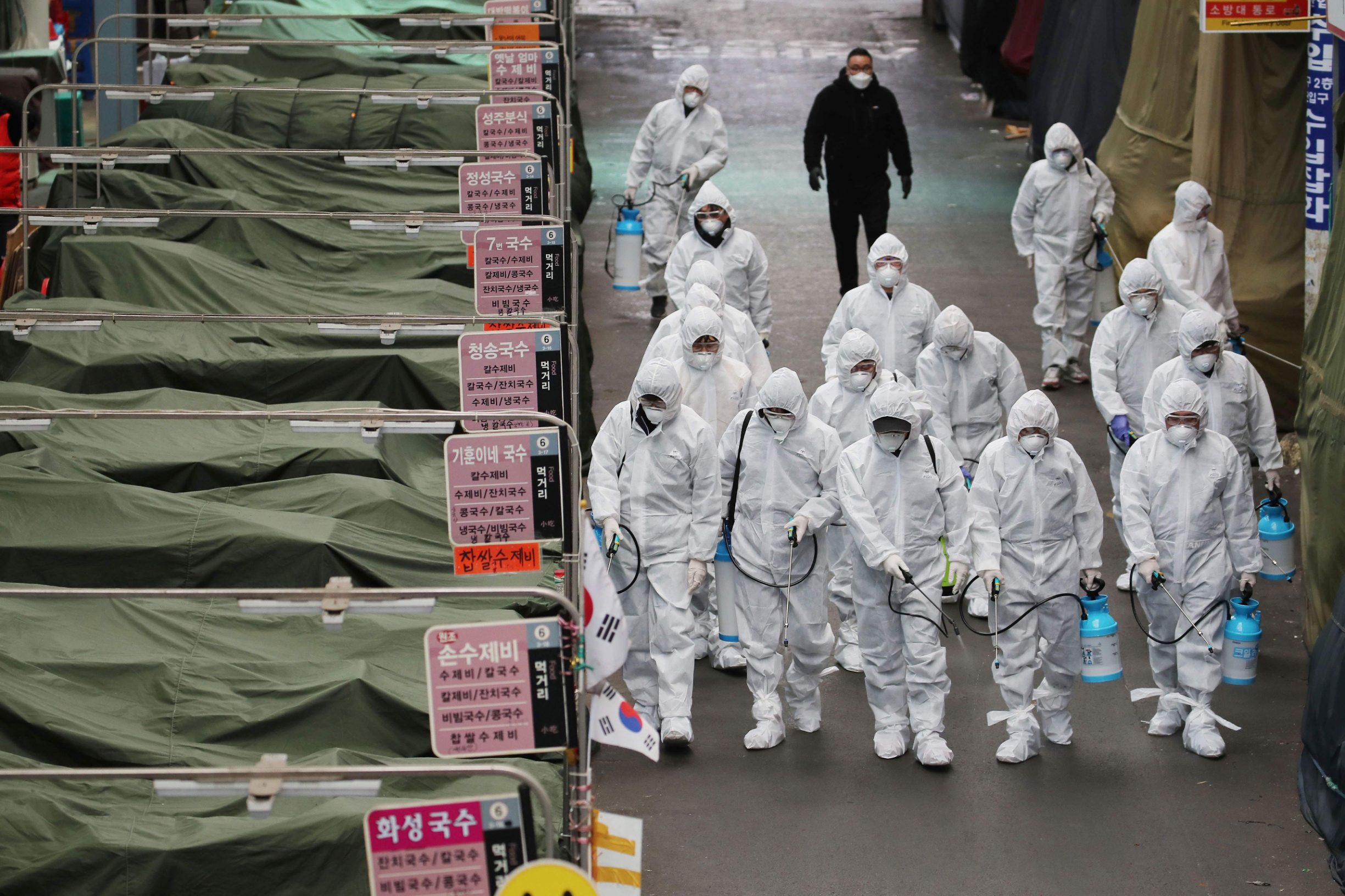 Market workers wearing protective gear spray disinfectant at a market in the southeastern city of Daegu on February 23, 2020 as a preventive measure after the COVID-19 coronavirus outbreak. - South Korea reported two additional deaths from coronavirus and 123 more cases on February 23, with nearly two thirds of the new patients connected to a religious sect. The national toll of 556 cases is now the second-highest outside of China. (Photo by - / YONHAP / AFP) / - South Korea OUT / REPUBLIC OF KOREA OUT  NO ARCHIVES  RESTRICTED TO SUBSCRIPTION USE