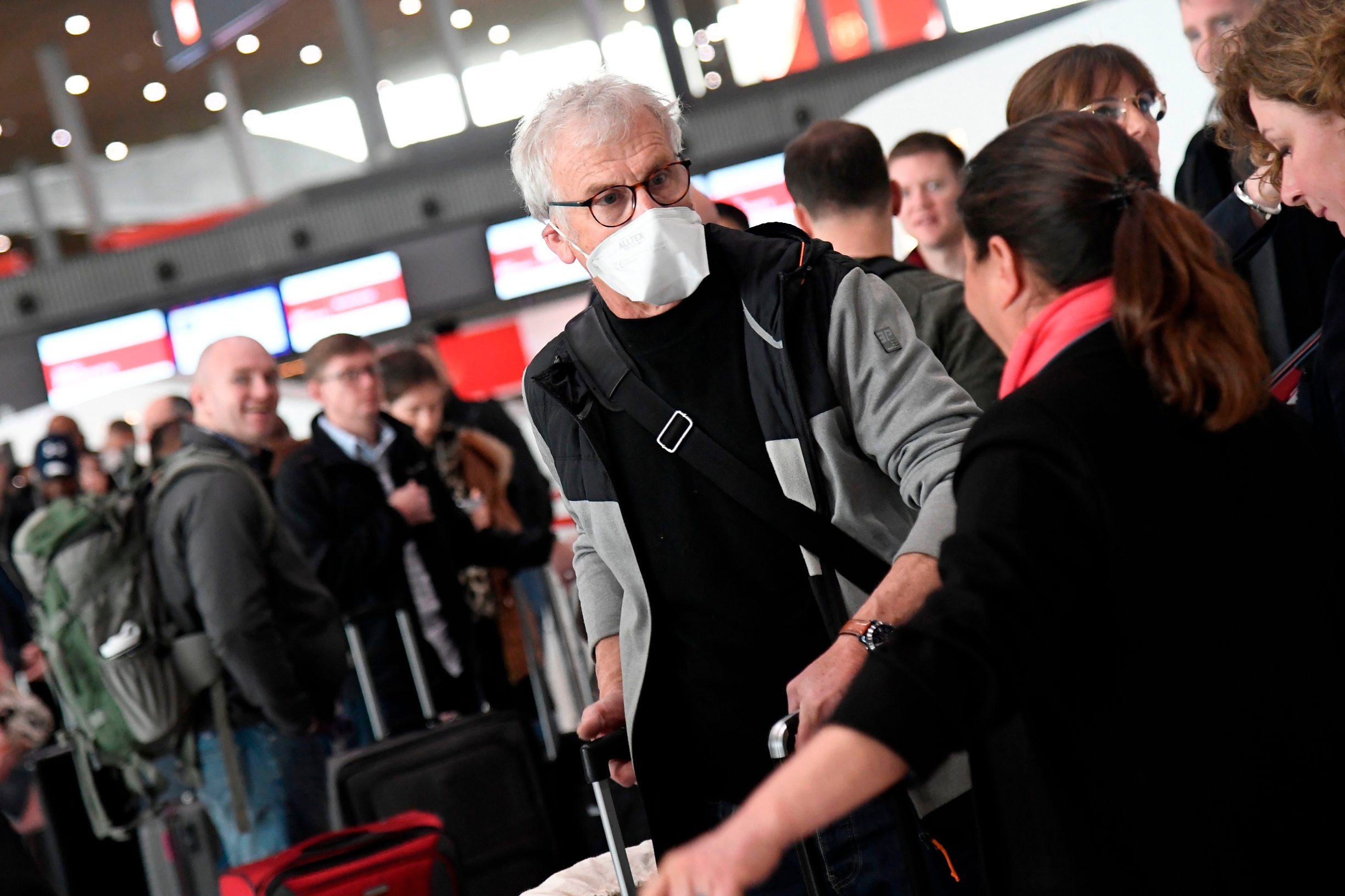 Travellers with protective face masks wait in a check-in line at Paris-Charles-de-Gaulle airport after a US 30-day ban on travel from Europe due to the COVID-19 spread in Roissy-en-France on March 12, 2020. - US President Donald Trump announced on March 11, 2020 a shock 30-day ban on travel from mainland Europe over the coronavirus pandemic that has sparked unprecedented lockdowns, widespread panic and another financial market meltdown. (Photo by Bertrand GUAY / AFP)