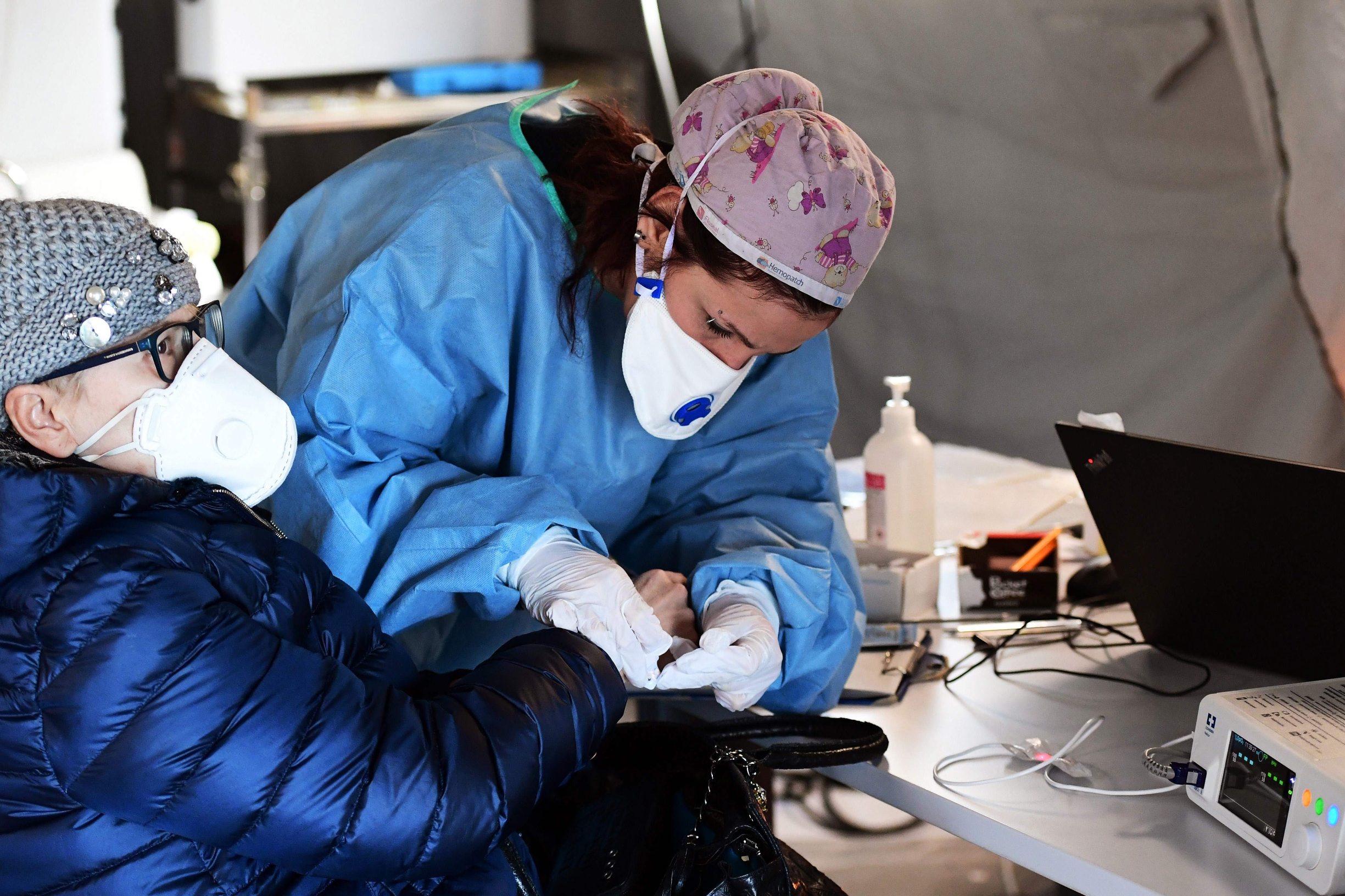 A ederly woman receives assistance in the a pre-triage medical tent in front of the Cremona hospital, in Cremona, northern Italy, on March 4, 2020. - Italy will recommend people stop kissing in public, avoid shaking hands and keep a safe distance from each other to limit the spread of the novel coronavirus. Other measures to be approved by the government, which has borne the brunt of the COVID-19 disease, includes a plan to play all football matches behind closed doors. (Photo by Miguel MEDINA / AFP)