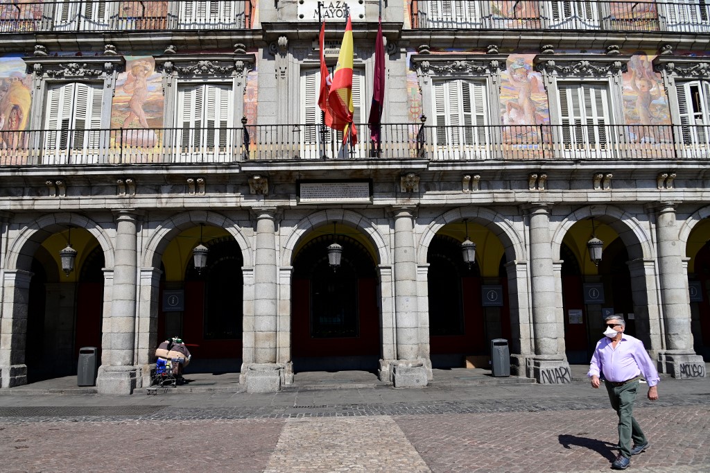 A man wearing a protective face mask walks at the usually overcrowded Plaza Mayor in central Madrid on March 14, 2020 after regional authorities ordered all shops in the region be shuttered from today through March 26, save for those selling food, chemists and petrol stations, in order to slow the coronavirus spread. (Photo by JAVIER SORIANO / AFP)