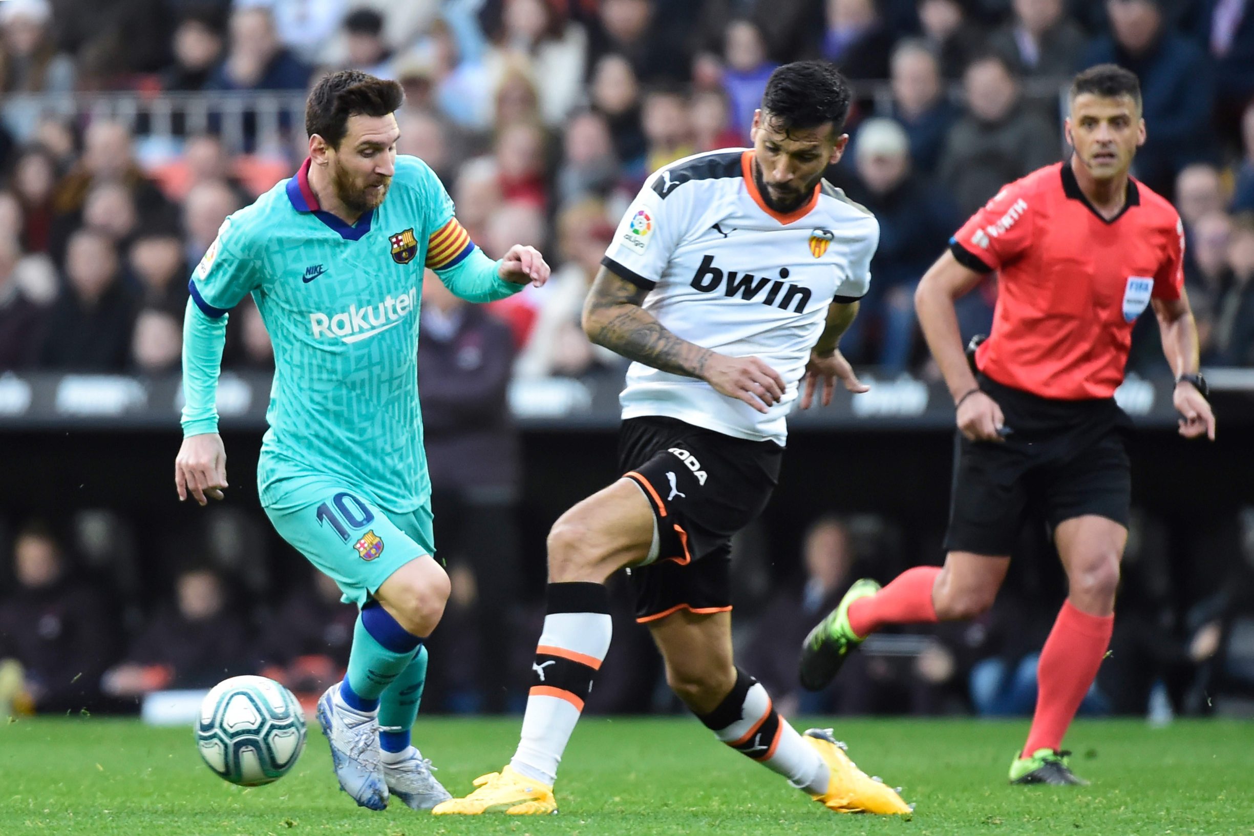 Valencia's Argentinian defender Ezequiel Garay (C) challenges Barcelona's Argentine forward Lionel Messi(L) during the Spanish league football match Valencia CF against FC Barcelona at the Mestalla stadium in Valencia on January 25, 2020. (Photo by JOSE JORDAN / AFP)