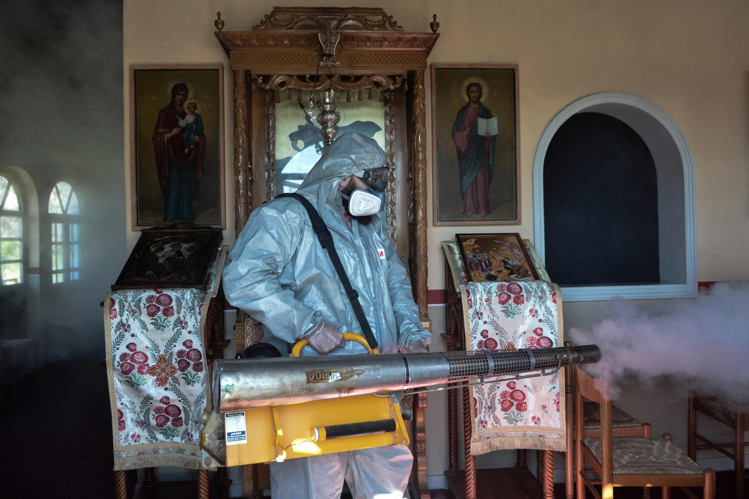 A worker disinfects a church in Thessaloniki on March 12, 2020. - Greece announced on March 12, 2020, its first death from the new coronavirus, a 60-year-old Greek man who traveled to Israel in late February. The majority of the 98 cases of coronavirus in Greece come from this group or from people who have been in contact with these pilgrims. Greece closed all schools, nurseries and universities on Tuesday for two weeks to 