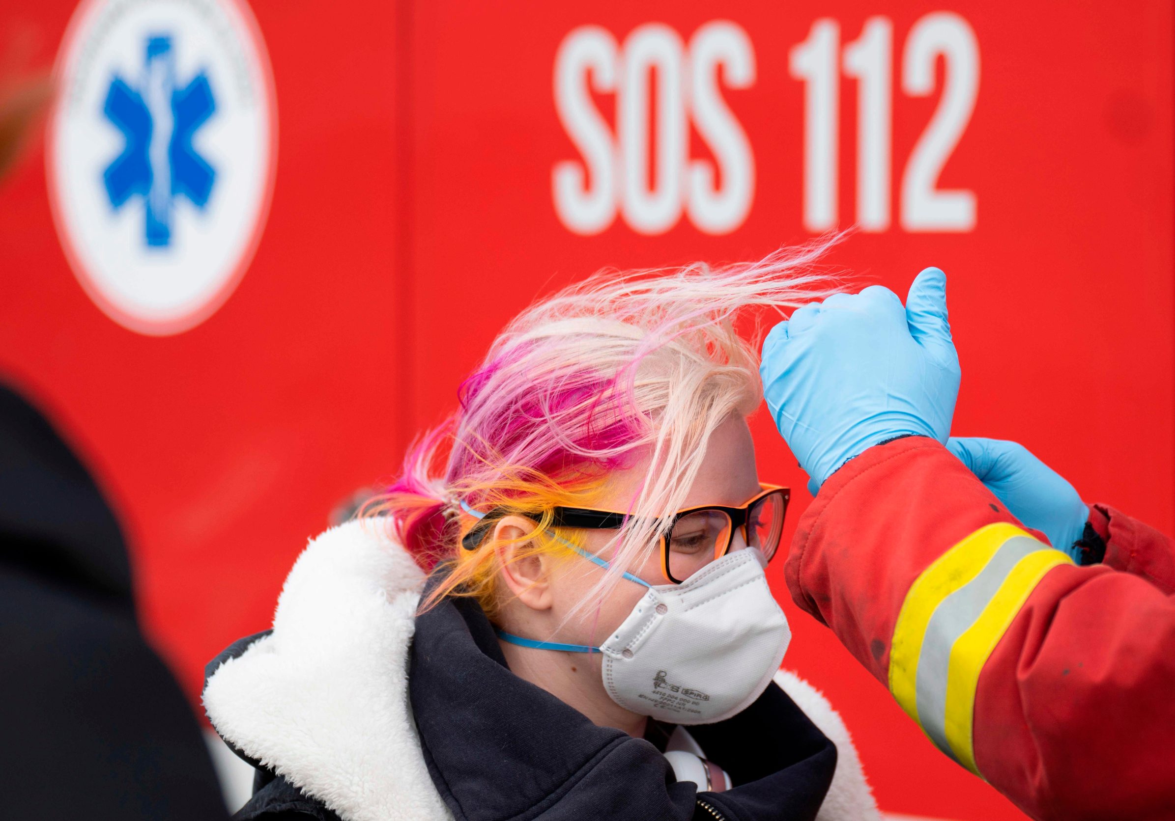 A Slovak firefighter checks the temperature of a woman wearing a protective facemask due to the coronavirus COVID-19 crossing the Bratislava-Jarovce border crossing between Austria and Slovakia on March 13, 2020. - The Slovak government has reintroduced controls along its borders with the exception of the Slovak-Polish border to prevent the new coronavirus from further spreading. Slovakia now only allows Slovak nationals to enter the country, or foreigners holding a Slovakian residency permit. All entrants will be isolated for 14 days. (Photo by JOE KLAMAR / AFP)