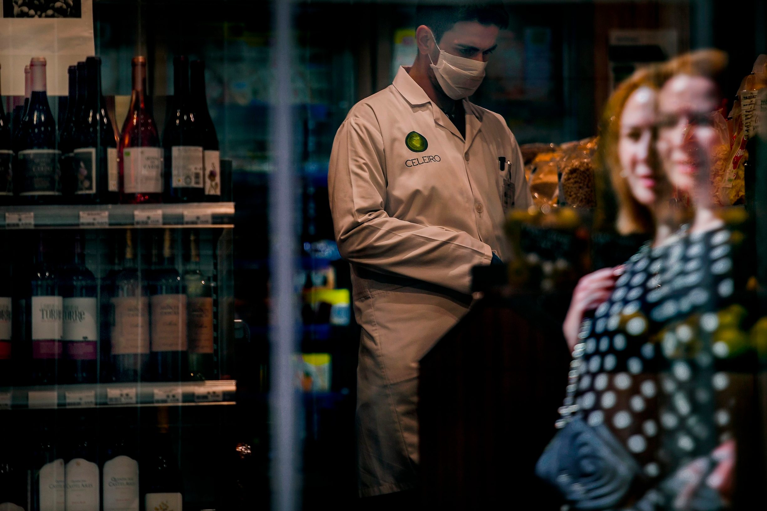 A woman walks past a supermarket where an employee wears a face mask in downtown Lisbon on March 14, 2020. - Portugal has so far reported 169 confirmed cases of coronavirus, far below neighboring Spain, where there are over 5,700 cases and dozens of fatalities. The governmnet has ordered schools to close next week due to the outbreak of the deadly virus, ordered nightclubs to close and imposed restrictions on the number of people who can visit restuarants. It has also announced that cruise ships would not be allowed to disembark passengers except those living in Portugal. (Photo by PATRICIA DE MELO MOREIRA / AFP)