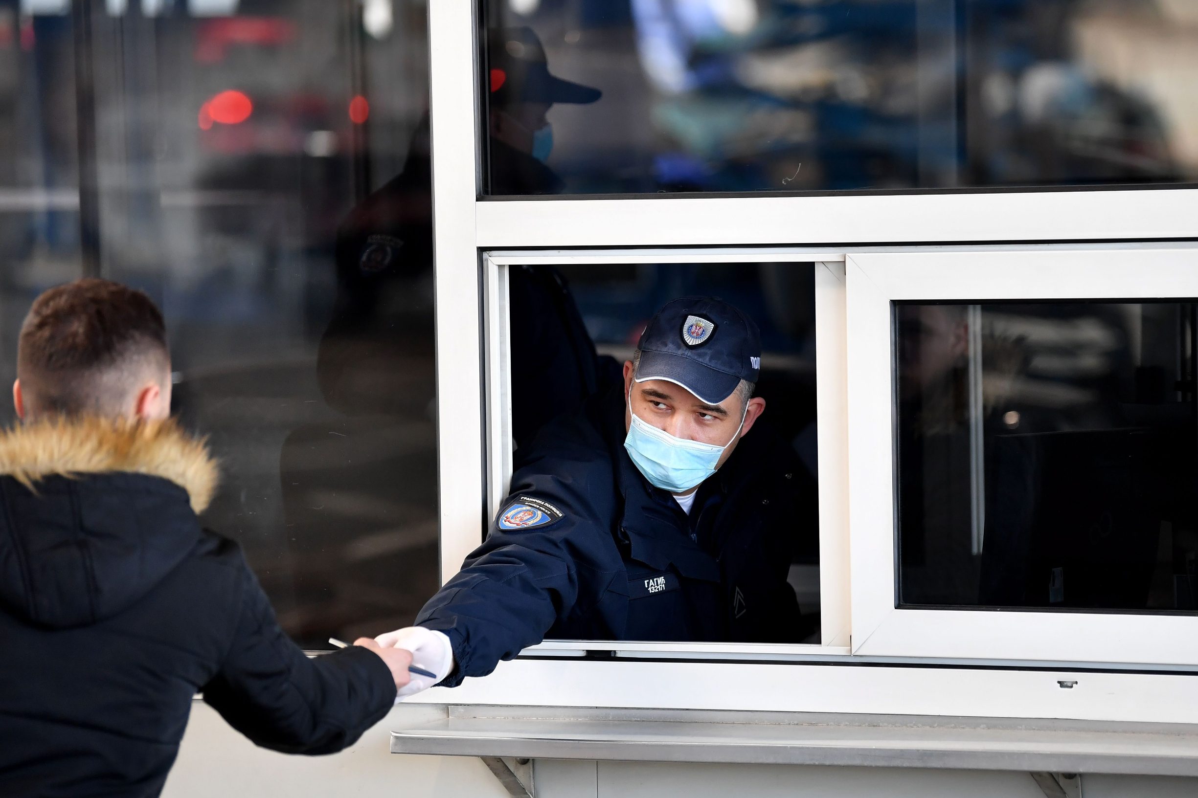 Serbian border police officer wearing a protective mask checks documents of a traveller on March 15, 2020, at the Batrovci border crossing between Serbia and Croatia. - Currently there are 46 positive cases of coronavirus COVID-19 in the Republic of Serbia. Serbian government temporarily prohibits the entry of foreign nationals arriving from countries particularly affected by the virus. Serbian nationals coming from the affected area go to a mandatory solitary confinement at home, under medical supervision, for 14 days. Previously indoor mass events are cancelled, and no spectators at sporting events. The government has 