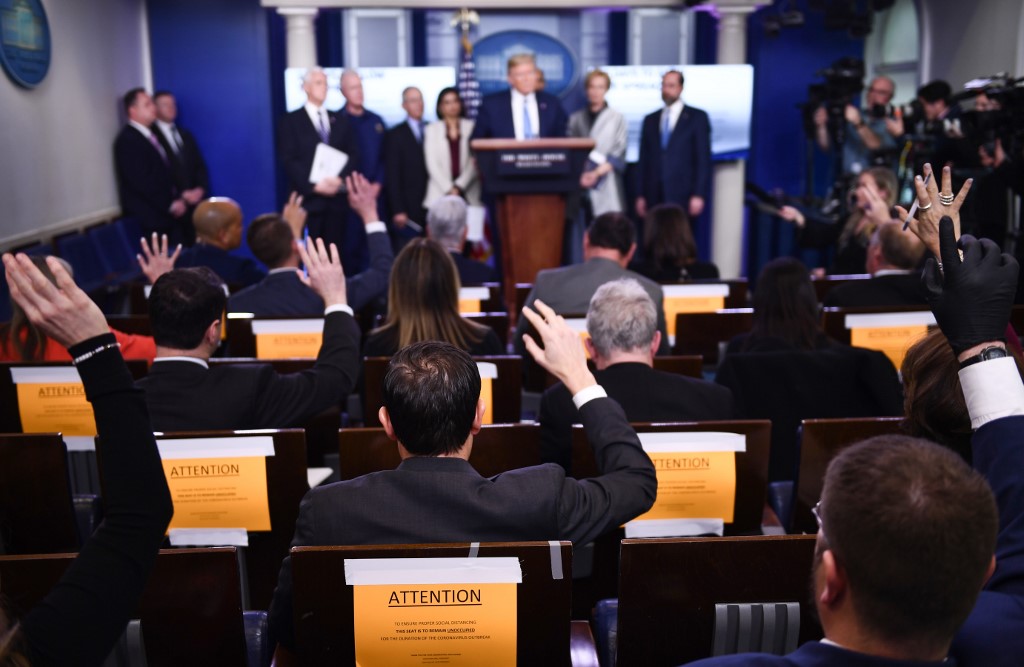 Reporters ask questions as US President Donald Trump speaks during a press briefing at the White House in Washington, DC, on March 16, 2020. - The first human trial to evaluate a candidate vaccine against the new coronavirus has begun in Seattle, US health officials said, raising hopes in the global fight against the disease. (Photo by Brendan Smialowski / AFP)