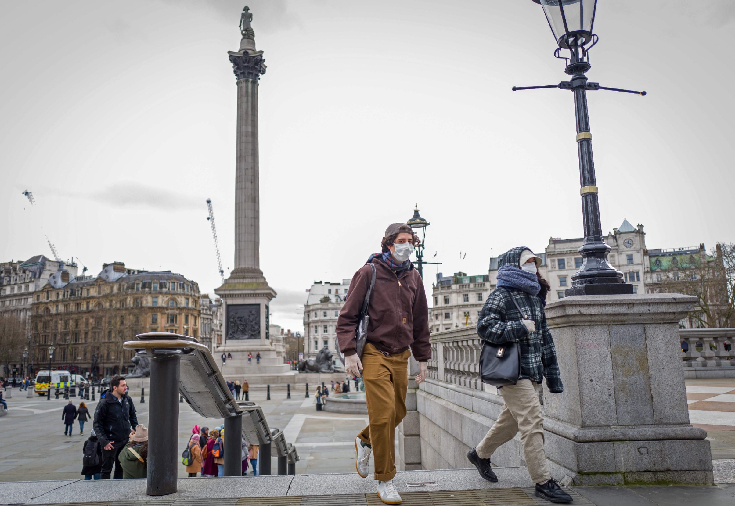 A man and a woman wearing protective face masks leave Trafalgar Square in central London on March 15, 2020. - britain on Sunday said its criticised plan to deal with coronavirus was designed to 