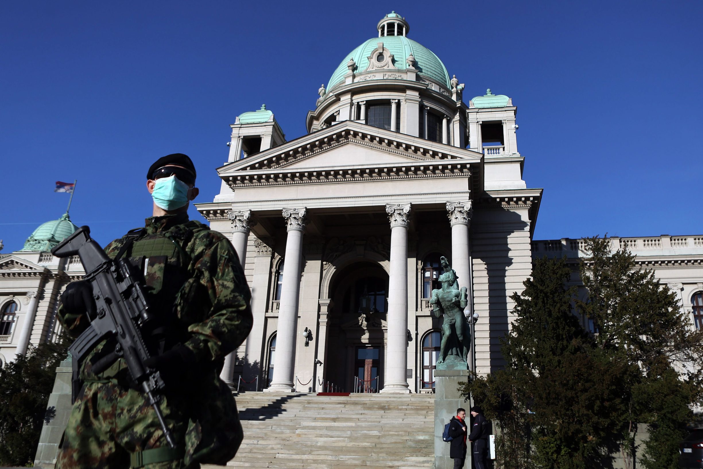 A Serbian Army soldier wearing gloves and a face masks as preventive measures against COVID-19 (novel Coronavirus) stands guard in front of the National Assembly in Belgrade on March 16, 2020. - Serbia declared a state of emergency on March 15, 2020 to halt the spread of the new coronavirus, shutting down many public spaces, deploying soldiers to guard hospitals and closing the borders to foreigners. Serbia's President Aleksandar Vucic said the new restrictions were necessary to 