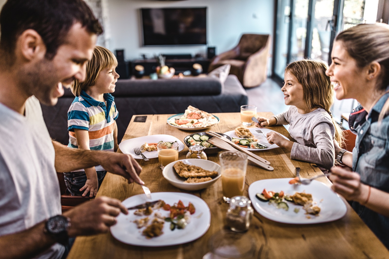 Happy family communicating during lunch time in dining room. Focus is on kids.