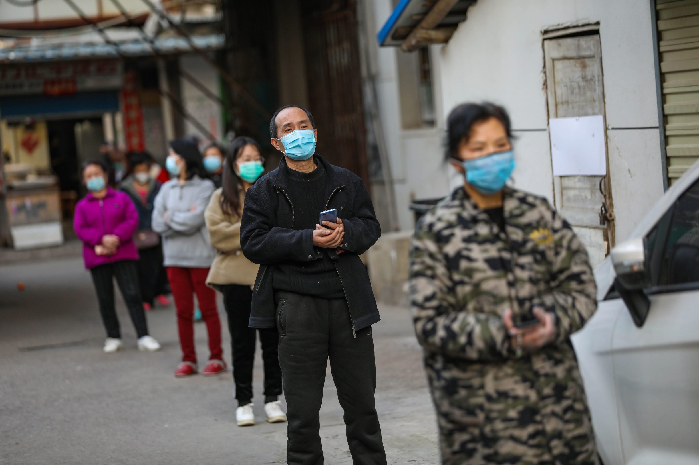 This photo taken on March 18, 2020 shows residents lining up to pick up pork which was delivered to their quarantined compound in Wuhan, in China's central Hubei province. - China on March 19 reported no new domestic cases of the coronavirus for the first time since it started recording them in January, but recorded a spike in infections from abroad. (Photo by STR / AFP) / China OUT