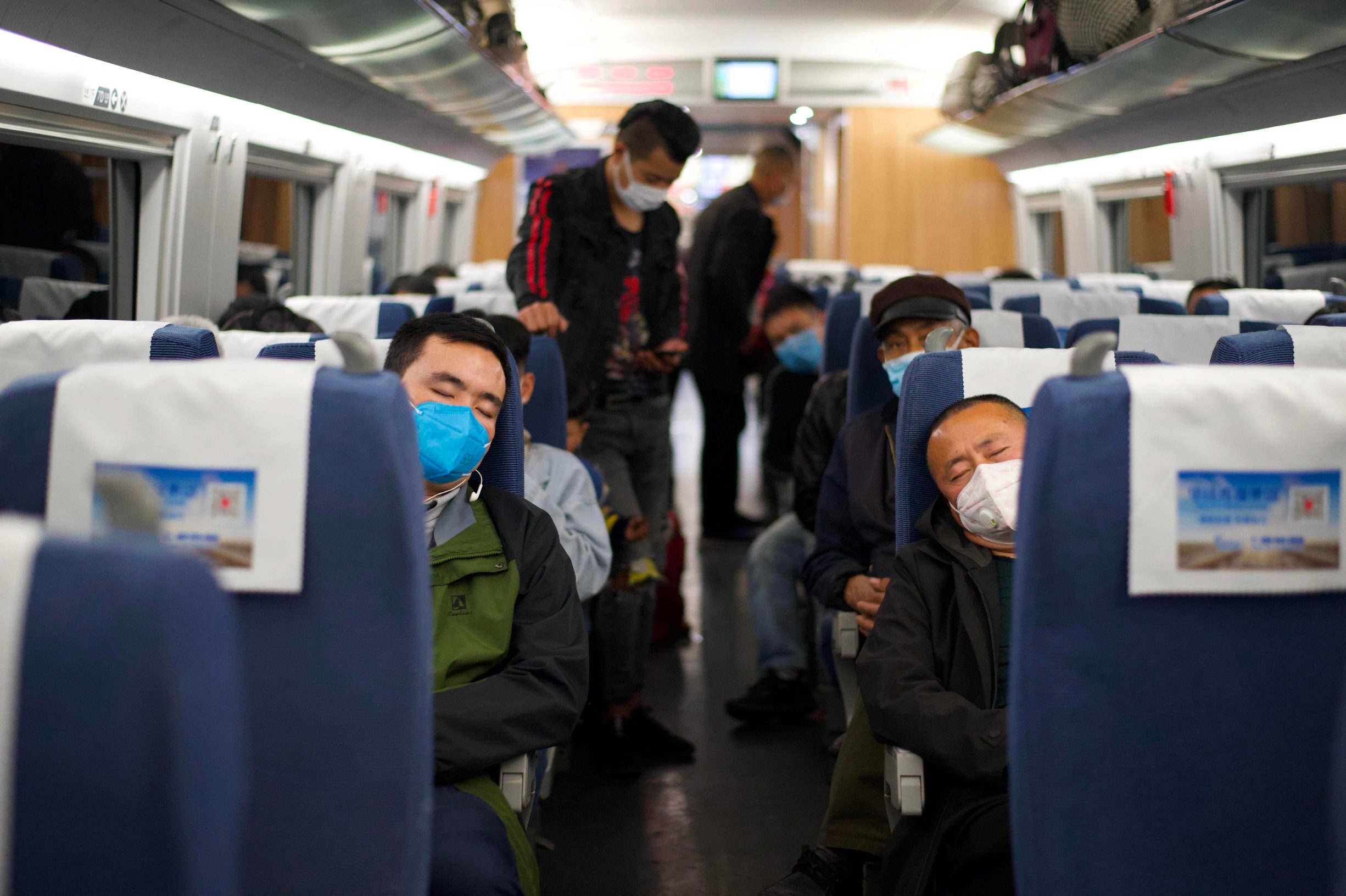 Passengers wearing face masks sleep as the train stops at the railway station in Macheng, in Chinas central Hubei province on March 25, 2020. - China lifted tough restrictions on the province at the epicentre of the coronavirus outbreak on March 25 after a months-long lockdown as the country reported no new domestic cases. (Photo by Noel Celis / AFP)