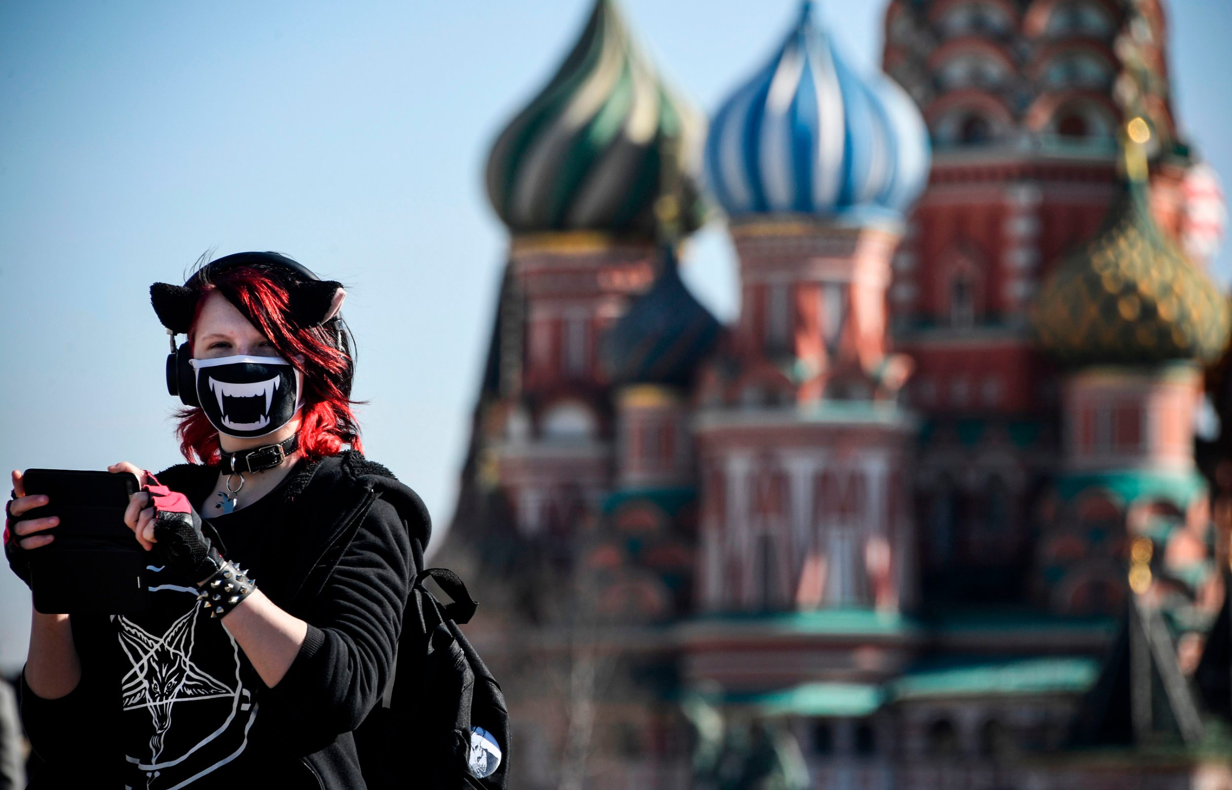TOPSHOT - A young woman wearing a face mask, amid concerns over the spread of the COVID-19 coronavirus, walks on Red Square in front of St. Basil's Cathedral in downtown Moscow on March 25, 2020. (Photo by Alexander NEMENOV / AFP)