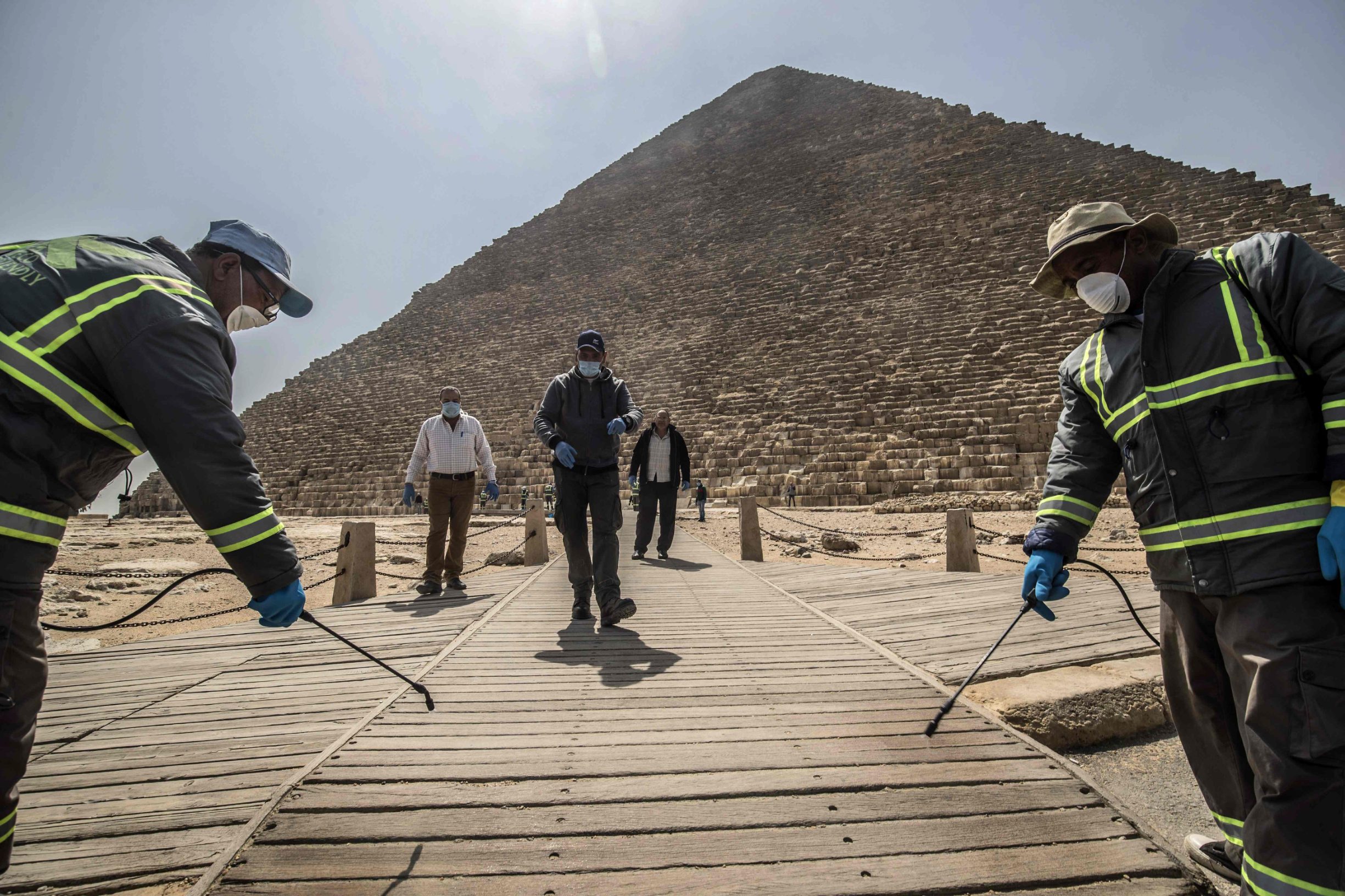 TOPSHOT - Egyptian municipality workers disinfect the Giza pyramids necropolis on the southwestern outskirts of the Egyptian capital Cairo on March 25, 2020 as protective a measure against the spread of the coronavirus COVID-19. (Photo by Khaled DESOUKI / AFP)