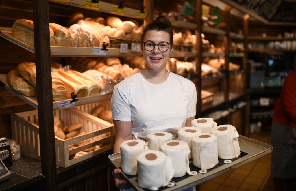 Apprentice Andrea Schulz presents a tablet with toilet paper shaped cakes at the bakery Schuerener Backparadies in Dortmund, western Germany, on March 26, 2020 amidst the spread of the novel coronavirus COVID-19. - The bakery of owner Tim Kortuem sells toilet paper cakes, which are spread with cream and wrapped in fondant. The sweet toilet paper rolls have become a 'bestseller' during the Corona crisis. (Photo by Ina FASSBENDER / AFP)