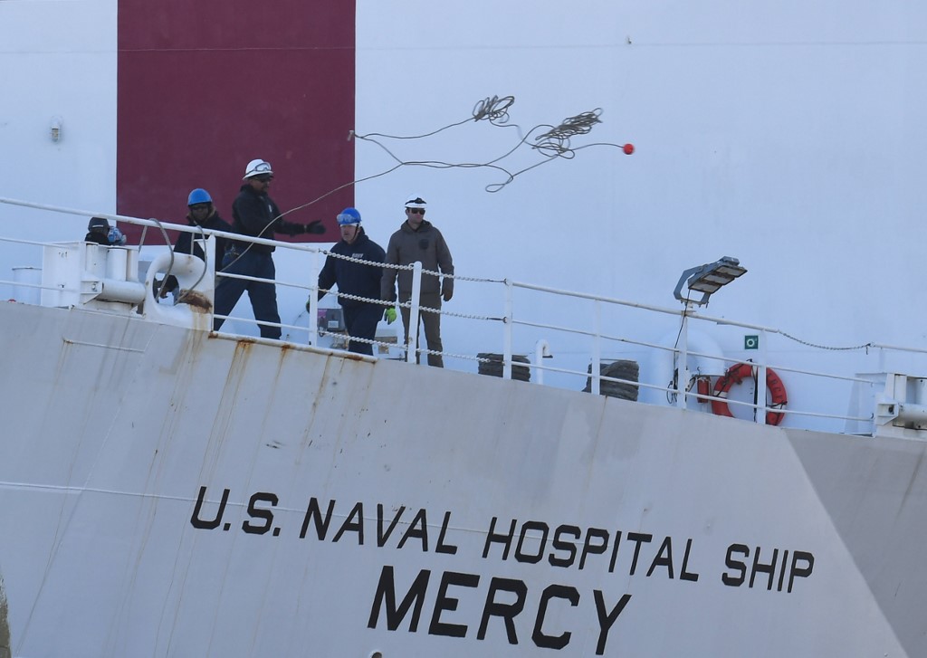 Crew members throw out a line to dock as the US Navy hospital ship Mercy arrives March 27, 2020 at the Port of Los Angeles to help local hospitals amid the growing coronavirus crisis, in Los Angeles, California. (Photo by Robyn Beck / AFP)
