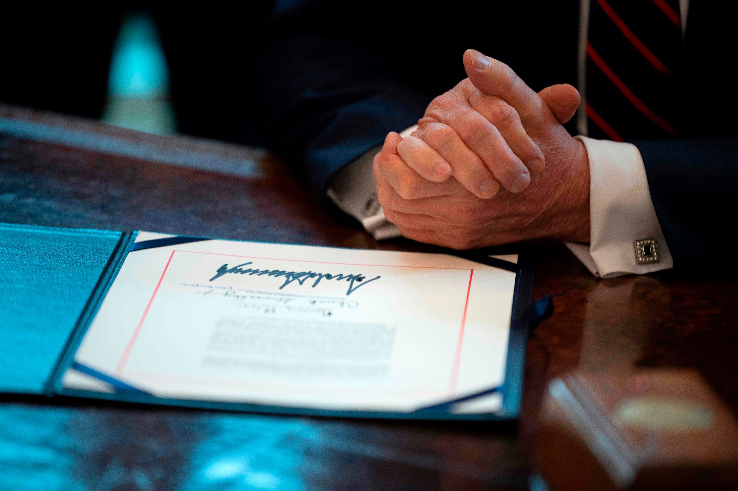 US President Donald Trump signs the CARES act, a  trillion rescue package to provide economic relief amid the coronavirus outbreak, at the Oval Office of the White House on March 27, 2020. - After clearing the Senate earlier this week, and as the United States became the new global epicenter of the pandemic with 92,000 confirmed cases of infection, Republicans and Democrats united to greenlight the nation's largest-ever economic relief plan. (Photo by JIM WATSON / AFP)