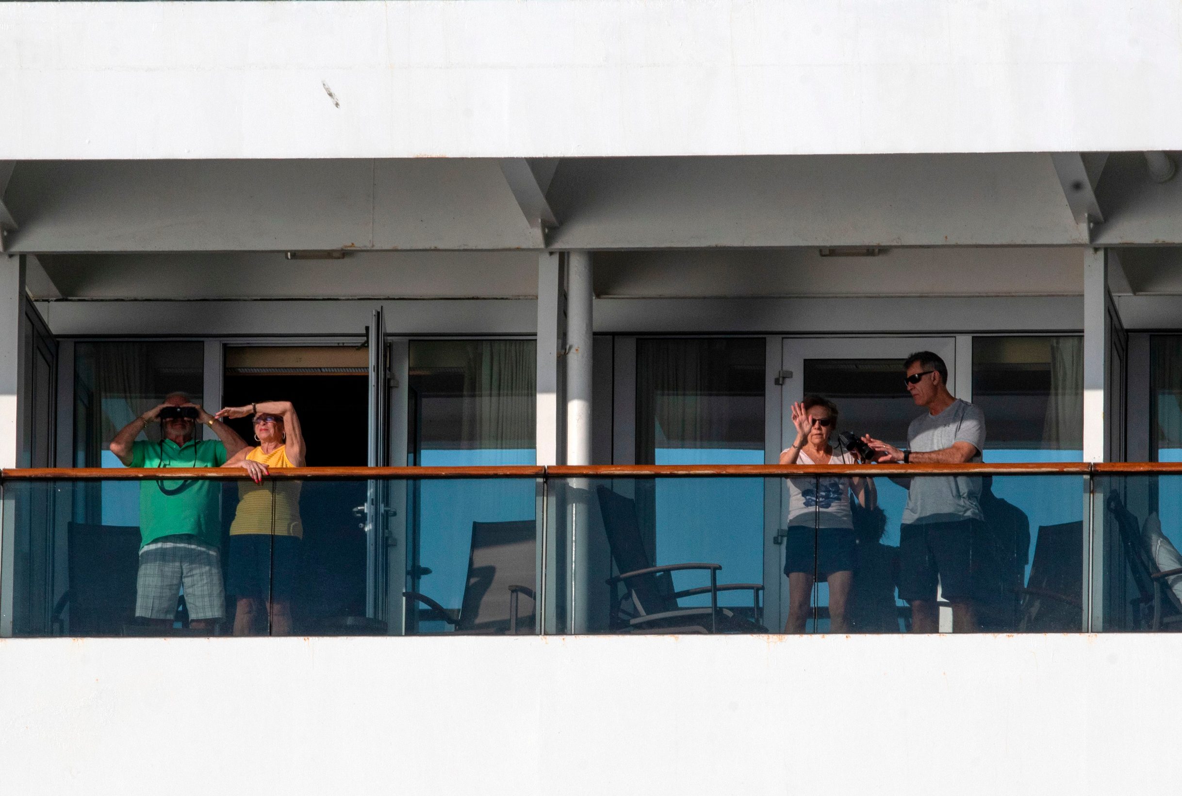 CORRECTION - Passengers use binoculars onboard Holland America's cruise ship Zaandam as it entered the Panama City bay to be assisted by the Rotterdam cruise ship with supplies, personnel and COVID-19 testing devices, eight milles off the coast of Panama City, on March 27, 2020. - Four passengers have died aboard a cruise ship carrying scores of people with flu-like symptoms that has been stranded off the Pacific coast of South America for several days, the liner company said Friday. The Zaandam, with 1,800 passengers on board, is currently in Panama's territorial waters, having been prevented from docking in several countries due to coronavirus fears. (Photo by Ivan PISARENKO / AFP) / The erroneous mention[s] appearing in the metadata of this photo by Ivan Pisarenko has been modified in AFP systems in the following manner: [Ivan Pisarenko] instead of [Luis Acosta]. Please immediately remove the erroneous mention[s] from all your online services and delete it (them) from your servers. If you have been authorized by AFP to distribute it (them) to third parties, please ensure that the same actions are carried out by them. Failure to promptly comply with these instructions will entail liability on your part for any continued or post notification usage. Therefore we thank you very much for all your attention and prompt action. We are sorry for the inconvenience this notification may cause and remain at your disposal for any further information you may require.