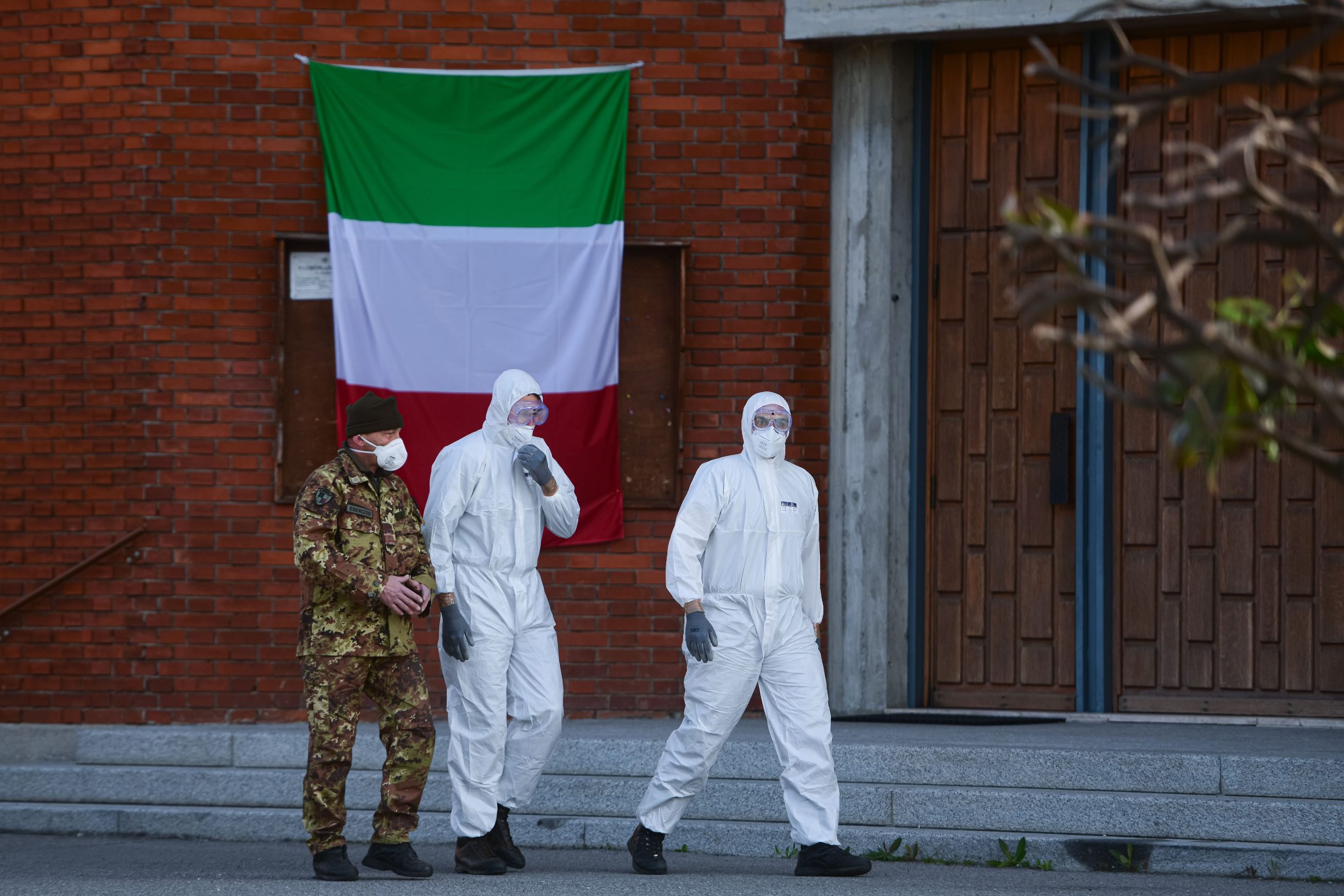Military personnel walk past an Italian flag outside the church of San Giuseppe in Seriate, Italy on March 28, 2020, as coffins of people deceased from the COVID-19 novel coronavirus are carried to be blessed inside the church. (Photo by Piero CRUCIATTI / AFP)